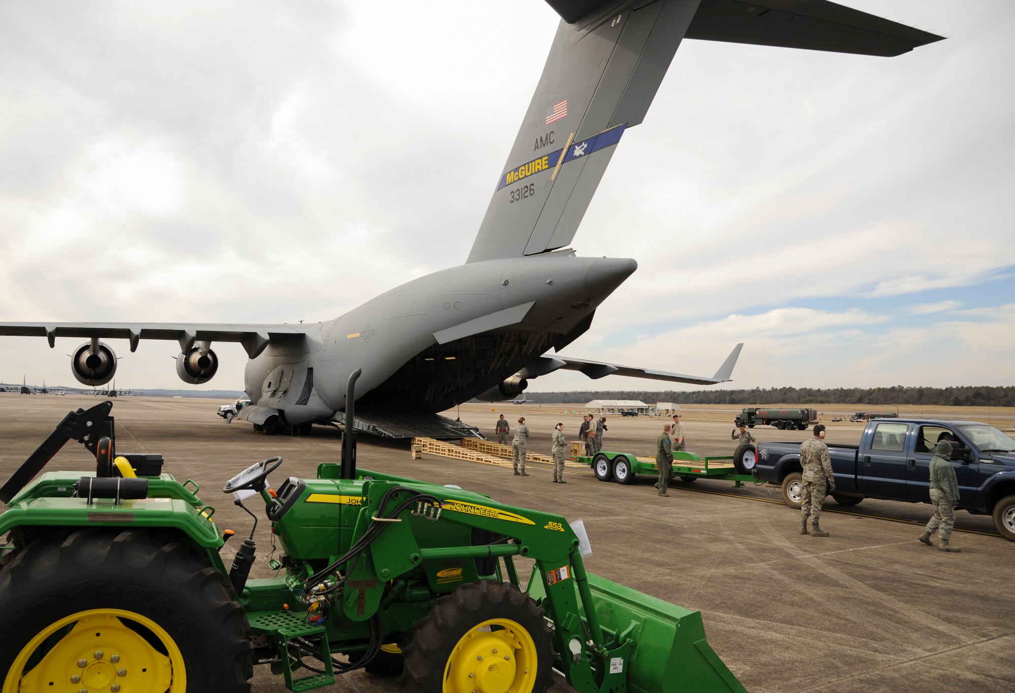 A team of “port dawgs” prepares to load a tractor and trailer onto a C-17 Feb. 13, 2015, at Little Rock Air Force Base, Ark. The supplies were donated by a local Arkansas organization for delivery to Haiti by Airmen as part of humanitarian efforts.  (U.S. Air Force photo by Airman 1st Class Harry Brexel)  