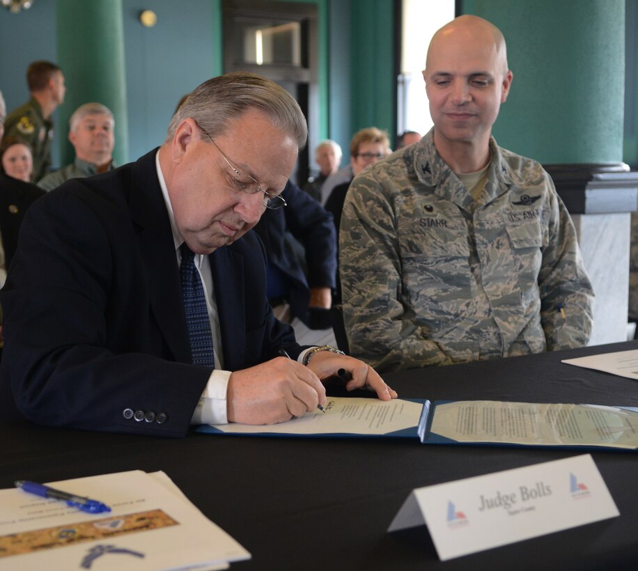 Judge Downing Bolls, Taylor County judge, signs a charter, while Col. Michael Bob Starr, 7th Bomb Wing commander watches April 1, 2015, at The Grace Museum in Abilene, Texas.  The charter was signed by various community leaders, making official the partnership between Dyess Air Force Base and the local community through the Air Force Community Partnership Program. (U.S. Air Force photo by Airman 1st Class Autumn Velez/Released)