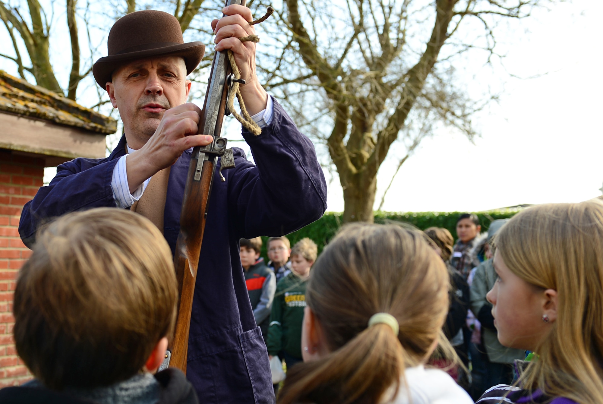 Liberty Intermediate School students listen as Nigel Amies, Norfolk Museum Service historical educator, discusses colonial muskets at Royal Air Force Lakenheath, England, March 27, 2015. The demonstration was part of a three-week pioneer life simulation for 4th and 5th grade Liberty Intermediate School students studying the colonial period. (U.S. Air Force photo by Airman 1st Class Erin R. Babis/Released)