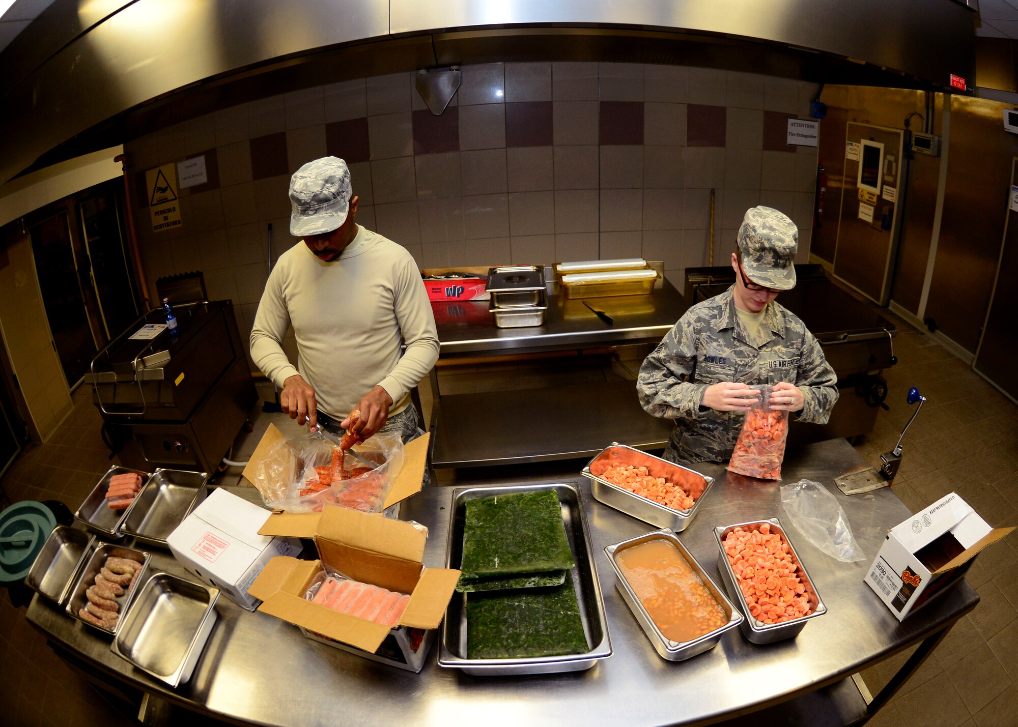 (From left) U.S. Air Force Senior Airmen Christopher Newsome and Angela Bowles, 31st Force Support Squadron food services journeymen, prepare lunch, April 1, 2015, at Aviano Air Base, Italy. La Dolce Vita provides four meals to an average of 550 guests per day. (U.S. Air Force photo by Senior Airman Areca T. Wilson/Released)