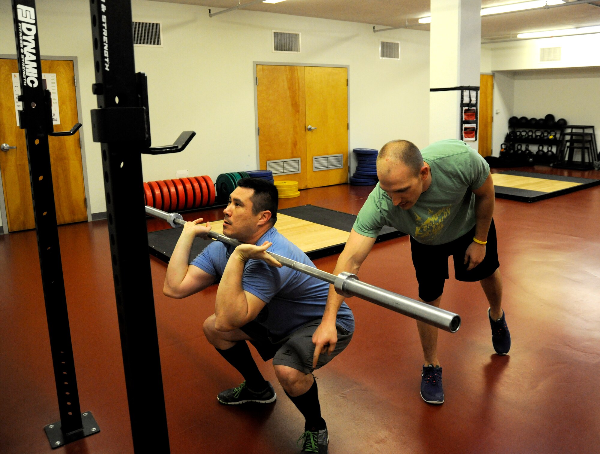 1st Lt. Corey Rakes, 65th Comptroller Squadron, instructs Tech Sgt. Daniel Bisel on the proper way to do a front squat at Lajes Field, Azores, Portugal, March 26, 2015. Rakes is a certified trainer for advance fitness programs. This fitness program offers Airmen the opportunity to experience a different style of workout routines. (U.S. Air Force photo by 1st Lt. Korey Fratini/Released)
