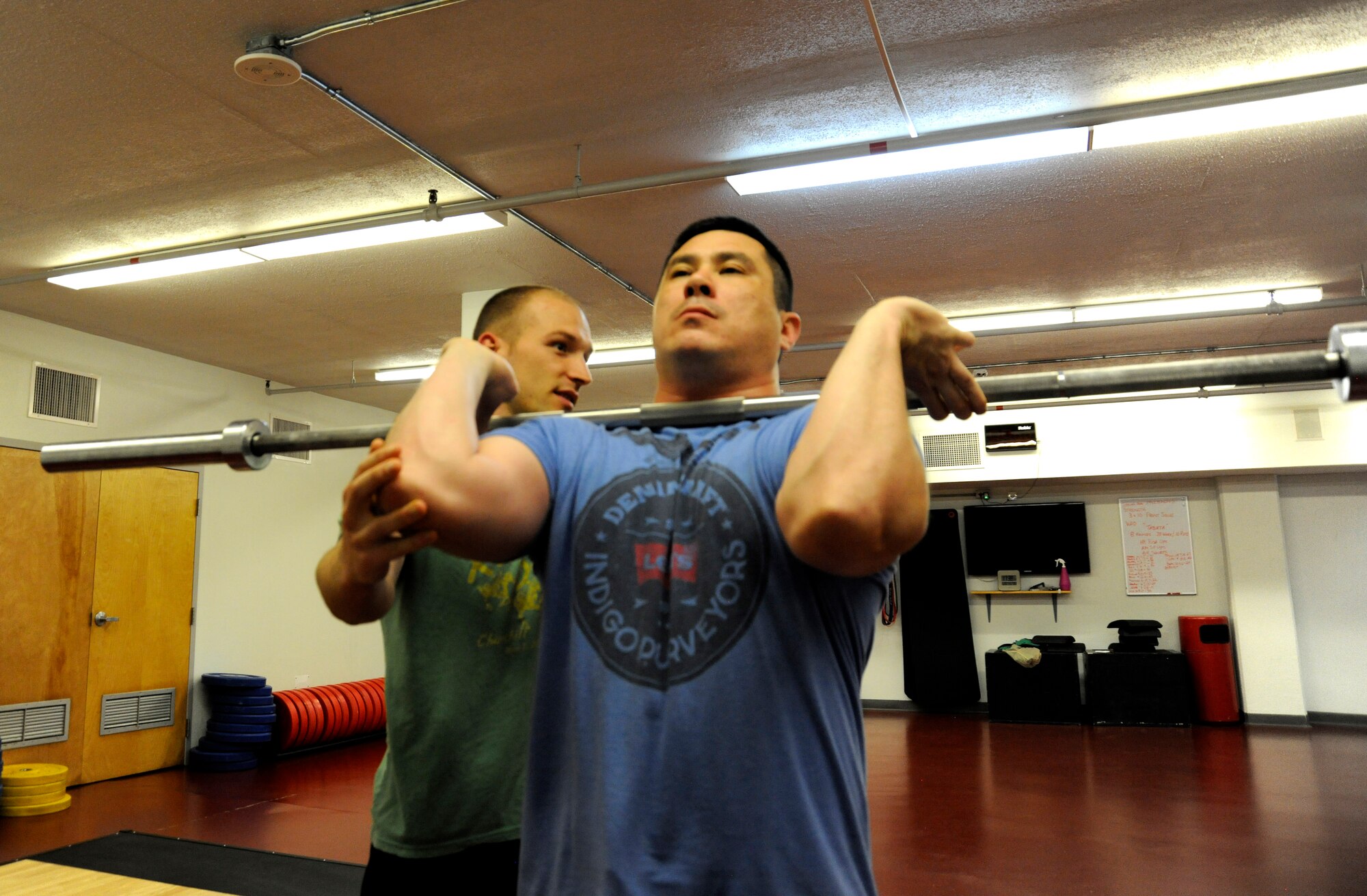 1st Lt. Corey Rakes, 65th Comptroller Squadron, instructs Tech Sgt. Daniel Bisel on the proper way to do a front squat at Lajes Field, Azores, Portugal, March 26, 2015. Rakes is a certified trainer for advance fitness programs. This fitness program offers Airmen the opportunity to experience a different style of workout routines. (U.S. Air Force photo by 1st Lt. Korey Fratini/Released)