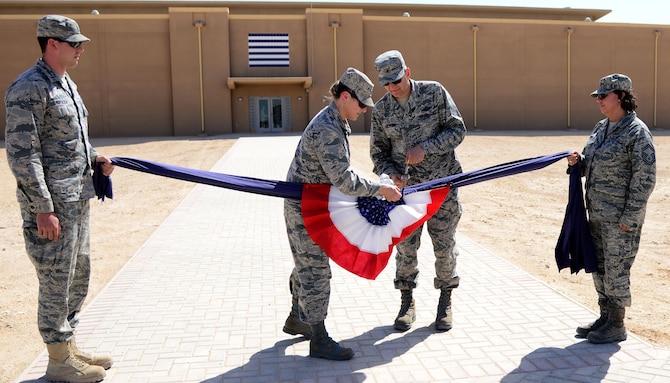 U.S. Air Force Col. Caroline Miller, 379th Expeditionary Mission Support Group commander, and Brig. Gen. Darren Hartford, 379th Air Expeditionary Wing commander, cut the ceremonial linen during a linen cutting ceremony, April 3, 2015, at Al Udeid Air Base, Qatar. The linen cutting ceremony symbolized the opening of the new Phase II dormitories in the Blatchford-Preston Complex. (U.S. Air Force photo by Senior Airman Kia Atkins)
