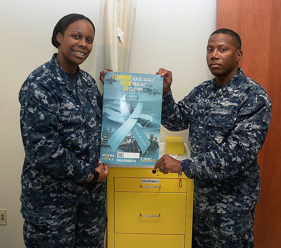 Petty Officer 1st Class Shaunta Johnson and Petty Officer 3rd Class Mario Fuller, victim advocates, Naval Branch Health Clinic, Albany aboard Marine Corps Logistics Base Albany, display a poster bearing the theme, "Eliminate Sexual Assault. Know your part. Do your part."