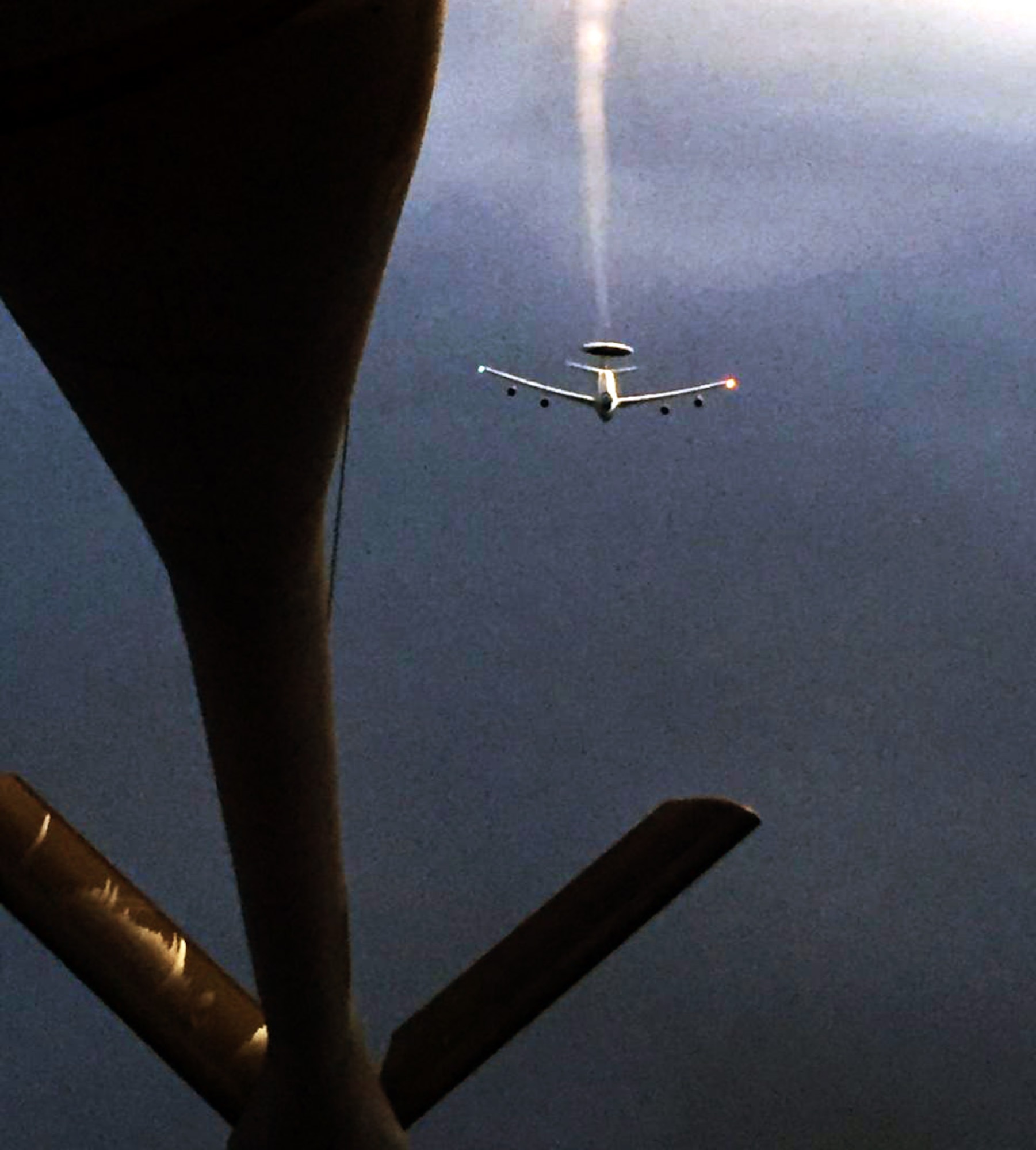 Contrails stream from the radar dome of an E-3 Sentry Airborne Warning and Control System (AWACS) as it closes in on the refueling boom of a KC-135 Stratotanker assigned to McConnell Air Force Base, Kan., during an evening air refueling training exercise, March 30, 2015. The KC-135 was operated by an aircrew made up of Air Force Reservists assigned to the 18th Air Refueling Squadron, 931st Air Refueling Group, at McConnell. The E-3 is equipped with a 30-foot rotating radar dome that contains a radar subsystem that permits surveillance from the Earth's surface up into the stratosphere, over land or water. The radar has a range of more than 250 miles (375.5 kilometers). The radar combined with an identification friend or foe, or IFF, subsystem can look down to detect, identify and track enemy and friendly low-flying aircraft by eliminating ground clutter returns that confuse other radar systems. (U.S. Air Force photo by Senior Master Sgt. Ray Lewis)