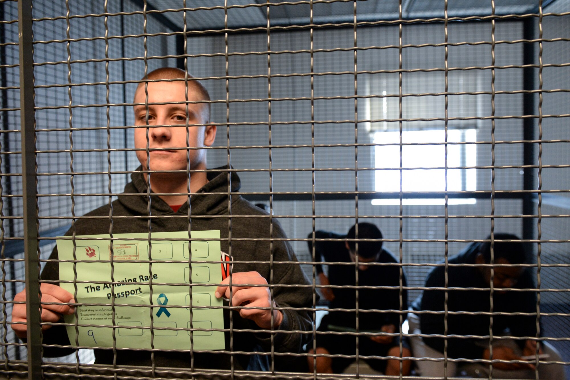 U.S. Air Force Airman 1st Class Korey Peters, a 354th Logistics Readiness Squadron vehicle management and analysis technician, takes a mug shot in the drunk tank cage during the 354th Fighter Wing “Amazing Race” as part of the Sexual Assault Awareness and Prevention month kickoff event at Eielson Air Force Base, Alaska, April 3, 2015. Peters and others who failed the simulated sobriety tests received a three-minute penalty in a  holding cage before being able to move on to the next race checkpoint. (U.S. Air Force photo by Senior Airman Peter Reft/Released)