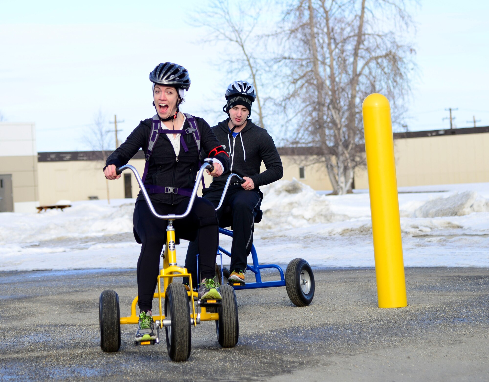 U.S. Air Force 1st Lt. Kelli Wood, the 354th Operations Support Squadron airfield operations flight commander, and 1st Lt. Chris Remsing, a 353rd Combat Training Squadron intelligence officer, ride the “tricycles of doom during the 354th Fighter Wing “Amazing Race” at Eielson Air Force Base, Alaska, April 3, 2015. Teams of two people had two hours to visit various locations on base and complete challenges as part of Sexual Assault Awareness and Prevention Month. (U.S. Air Force photo by Senior Airman Racheal E. Watson/Released)