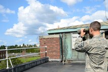 Master Sgt. Jason Torres, 627th Force Support Squadron first sergeant, uses a pair of binoculars from the top of the Office of Special Investigations building to view McChord Field during the OSI 201 Orientation briefing, Apr. 2, 2015, at Joint Base Lewis-McChord, Wash. A crucial part of the briefing was the importance of leaders and their units working with OSI and putting faith in the criminal investigative process. (U.S. Air Force photo/Senior Airman Rebecca Blossom)
