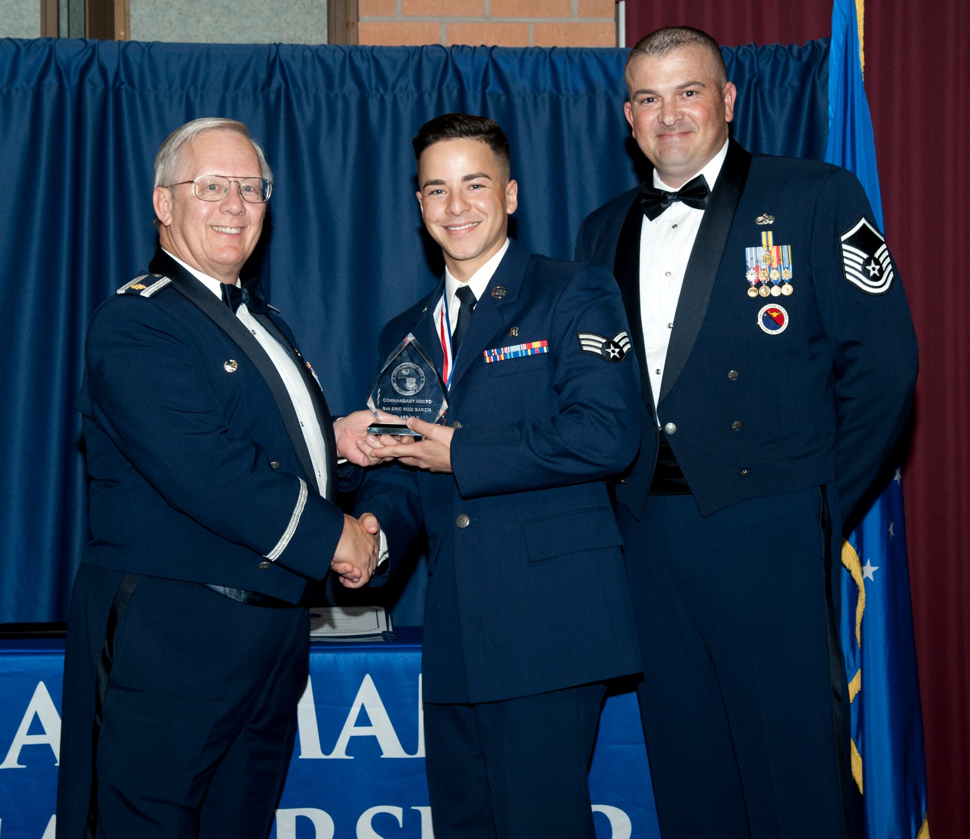 Eric Ruiz Garcia of the 71st Medical Support Squadron accepts the Commandant Award from retired Maj. George Pankonin and Master Sgt. James Goswick, the ALS commandant, March 25 during the first-ever Airman Leadership School graduation at Vance in the Vance Collocated Club. Pankonin was representing the Air Force Association who sponsored the award. (U.S. Air Force photo\ 2nd Lt. Isabel Crump)