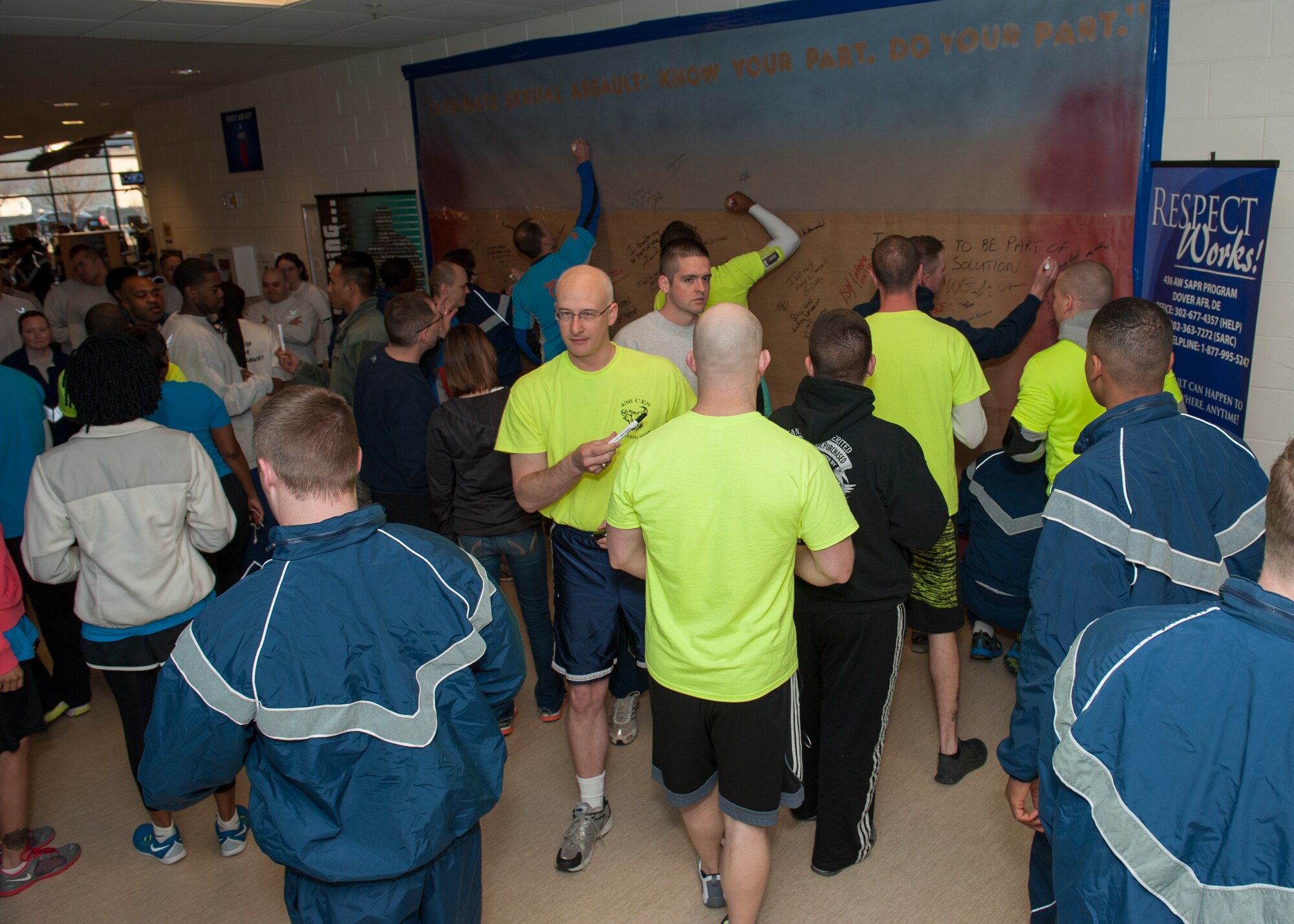 Team Dover Airmen sign the Sexual Assault Awareness and Prevention Month Graffiti Wall April 2, 2015, at the fitness center on Dover Air Force Base, Del. The graffiti wall was revealed directly prior to the Sexual Assault Prevention and Response 5 kilometer run/walk April 2, 2015, at the fitness center on Dover Air Force Base, Del. (U.S. Air Force photo/Airman 1st Class Zachary Cacicia)