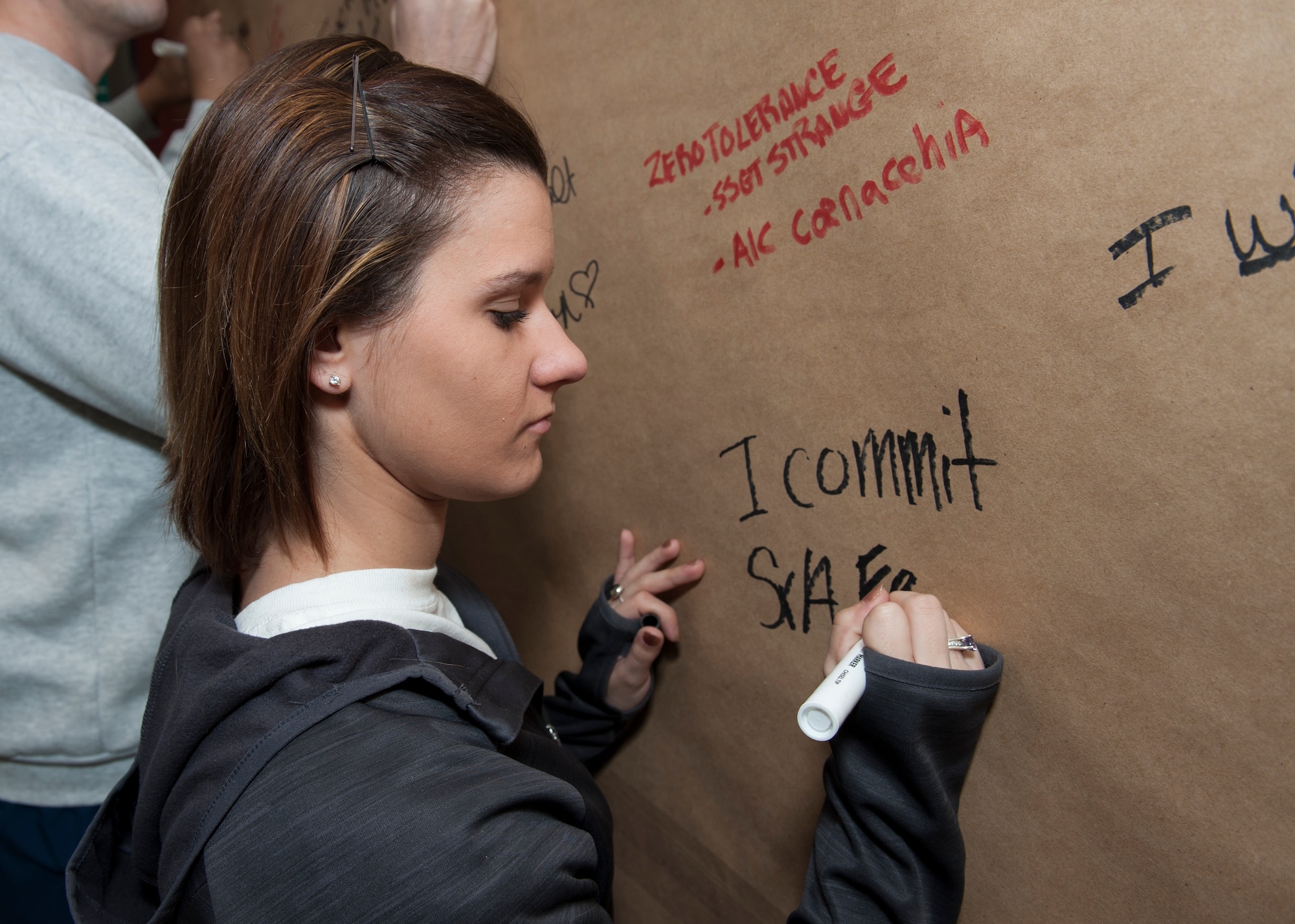 Senior Airman Ashlin Federick, 436th Airlift Wing Public Affairs community relations specialist, signs the Sexual Assault Awareness and Prevention Month Graffiti Wall April 2, 2015, at the fitness center on Dover Air Force Base, Del. Federick has been volunteering as a victim advocate for the past seven months. (U.S. Air Force photo/Airman 1st Class Zachary Cacicia)