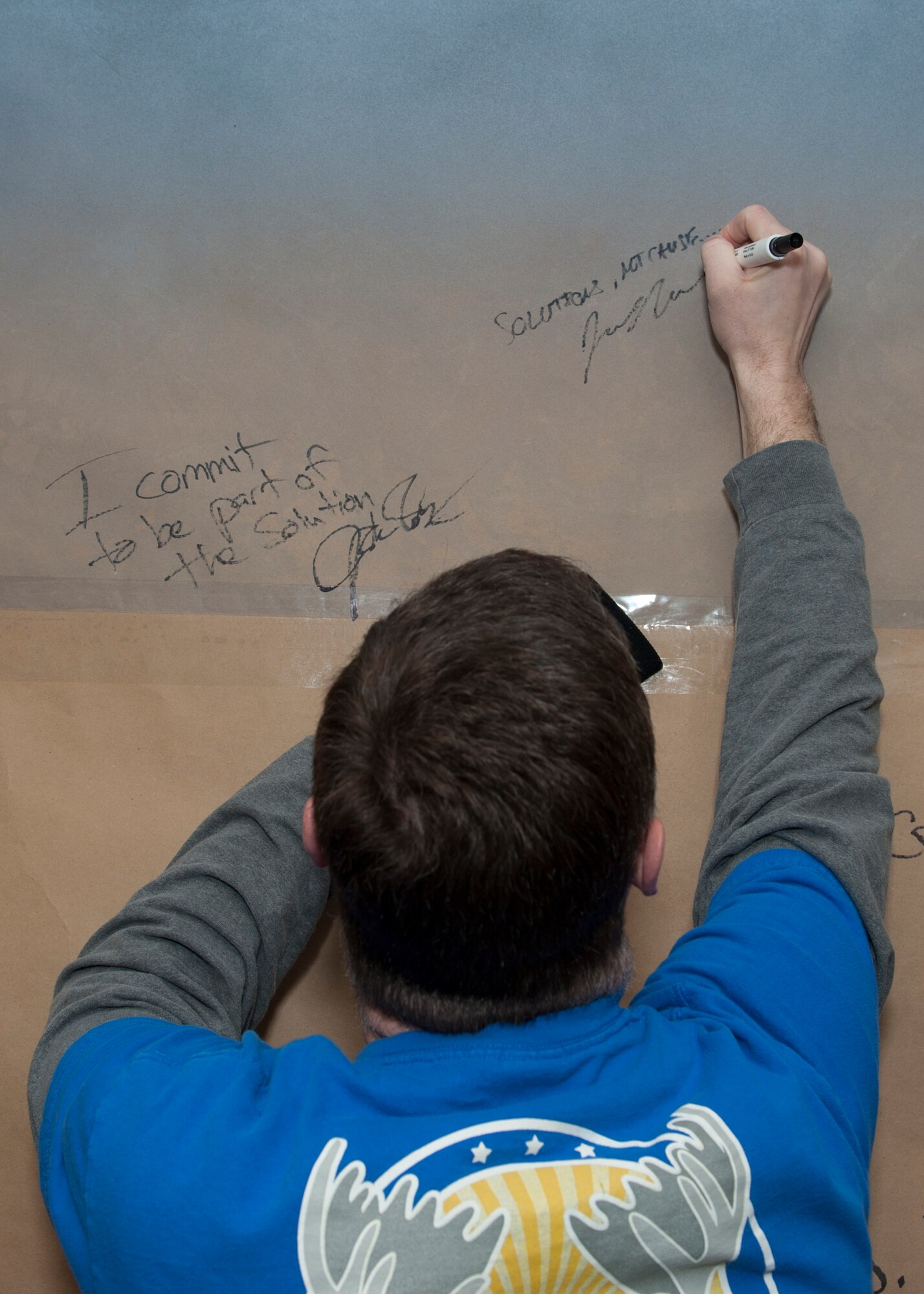 Lt. Col. Jason Mills, 3d Airlift Squadron commander, signs the Sexual Assault Awareness and Prevention Month Graffiti Wall April 2, 2015, at the fitness center on Dover Air Force Base, Del. Mills was one of dozens of Team Dover Airmen to show their support. (U.S. Air Force photo/Airman 1st Class Zachary Cacicia)