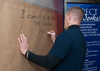 Col. Michael Grismer, 436th Airlift Wing commander, signs the Sexual Assault Awareness and Prevention Month Graffiti Wall April 2, 2015, at the fitness center on Dover Air Force Base, Del. This graffiti wall will be on display for the entire month of April. (U.S. Air Force photo/Airman 1st Class Zachary Cacicia)