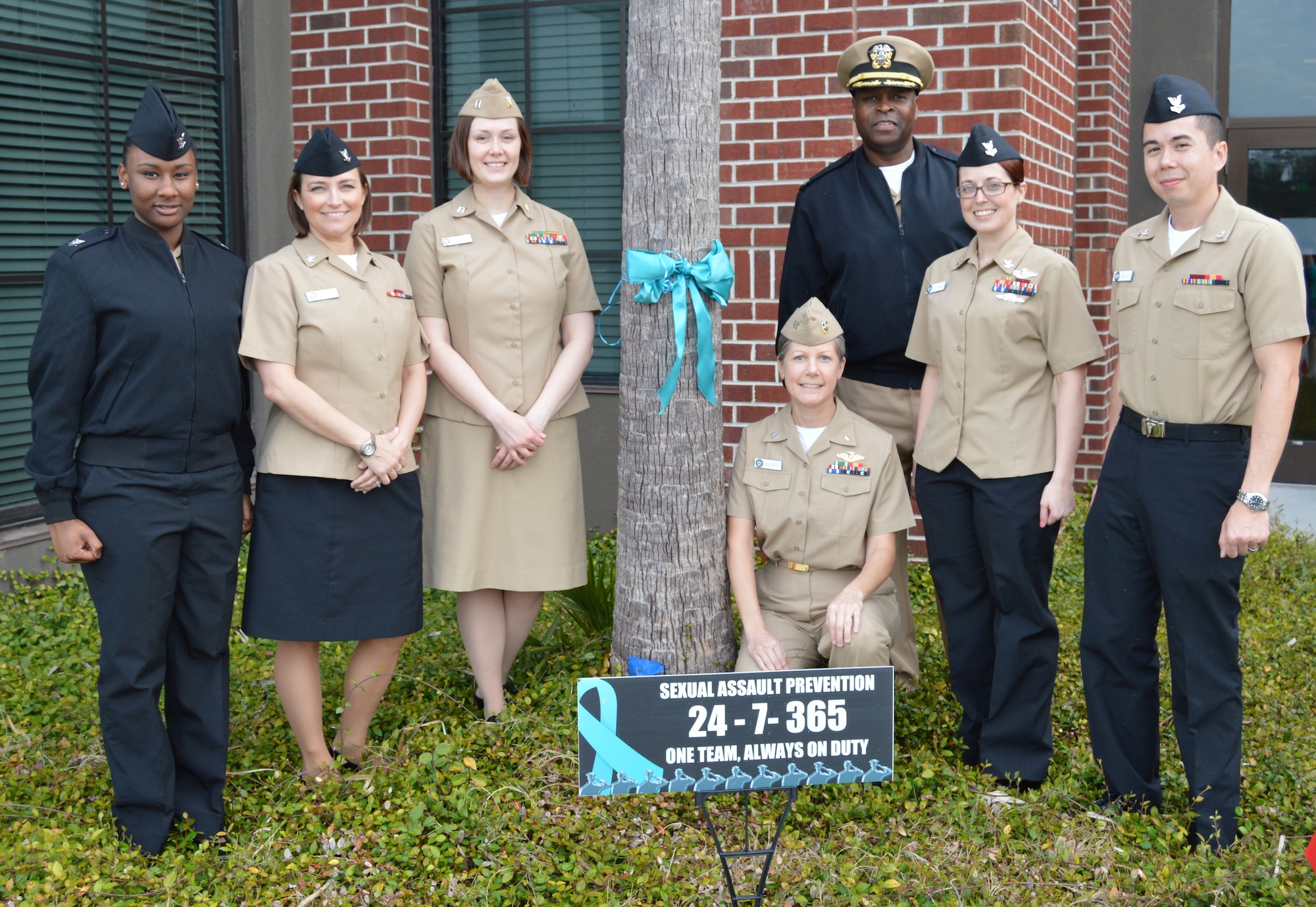 Naval Health Clinic Charleston Sexual Assault Prevention and Response representatives pose near a teal ribbon tied to tree in front of NHCC April 3 on Joint Base CHarleston, S.C., in honor of Sexual Assault Awareness Month. From left to right: Petty Officer 3rd Class Amanda Abrams, Petty Officer 3rd Class Nicole Johnson, Lt. Nikki Pritchard, Lt. Kristin Aucker, NHCC Commanding Officer Capt. Marvin Jones, Petty Officer 2nd Class Michele Coltrane and Petty Officer 2nd Class John Betts. (U.S. Navy photo/Kris Patterson)

