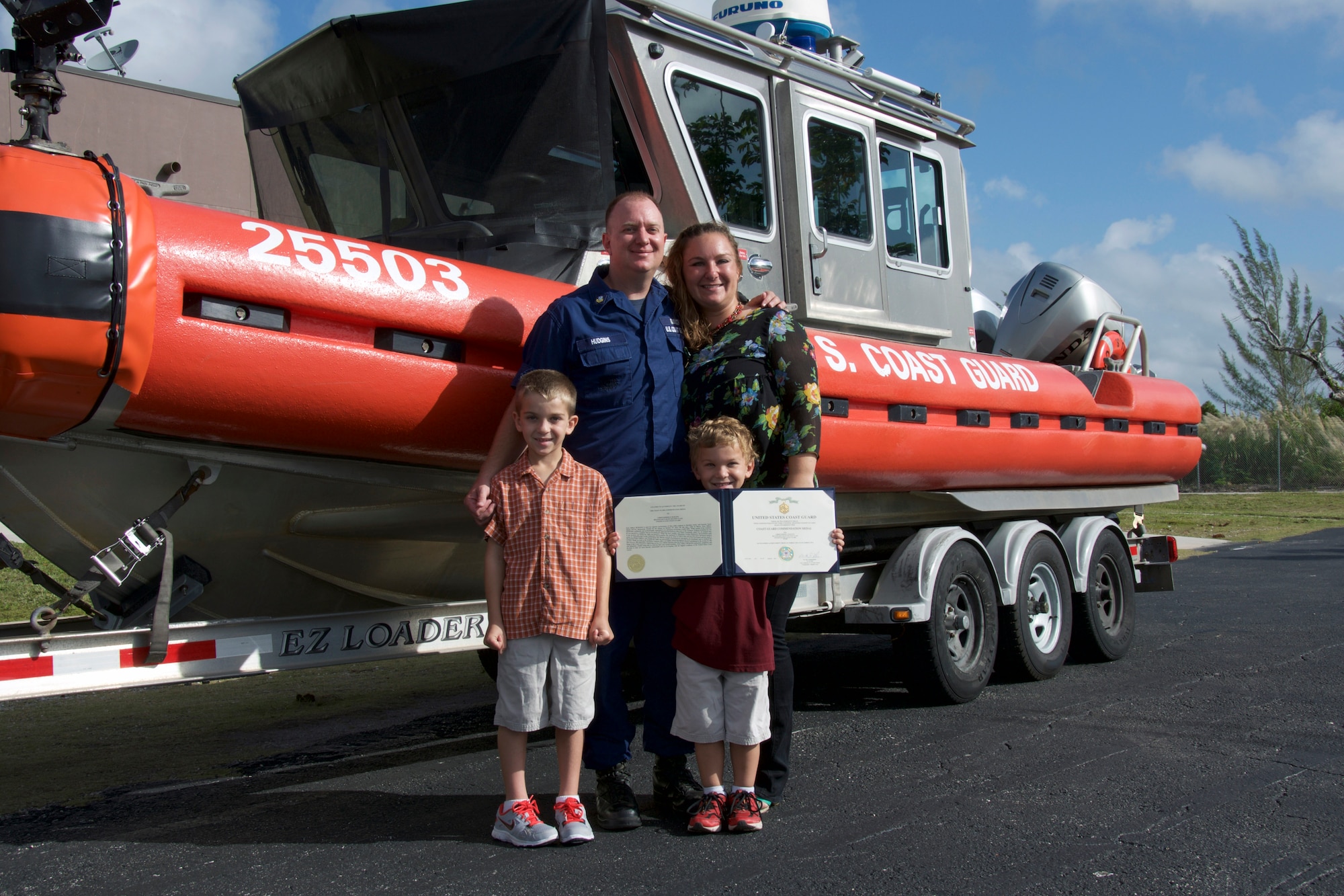 Petty Officer 2nd Class Christopher Hudgins, a Tactical Coxswain at Maritime Safety and Security Team Miami 91114, was presented with the Coast Guard Commendation Medal for saving the life of a child March 12. Hudgins is pictured with his wife, Stefanie, and sons, Cody and Shane. (U.S. Coast Guard photo)
