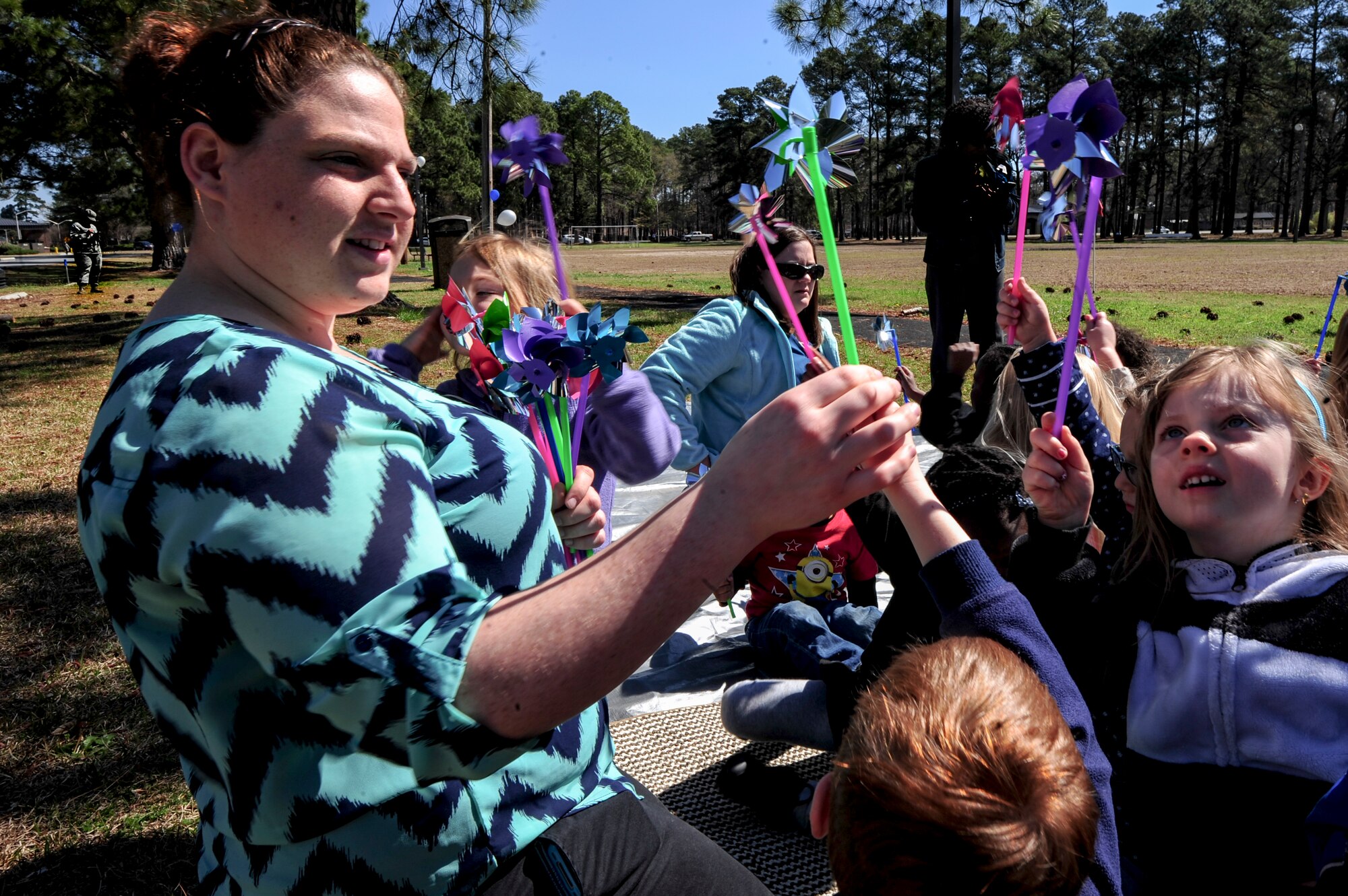 Dallas Peacock, an intern at the Child Development Center, hands out pinwheels to children of Team Seymour during a “Pinwheels for Child Abuse Prevention” event, April 1, 2015, at Seymour Johnson Air Force Base, North Carolina. More than 300 pinwheels were planted in the base’s pinwheel garden in support of child abuse prevention. (U.S Air Force photo/Senior Airman Brittain Crolley)