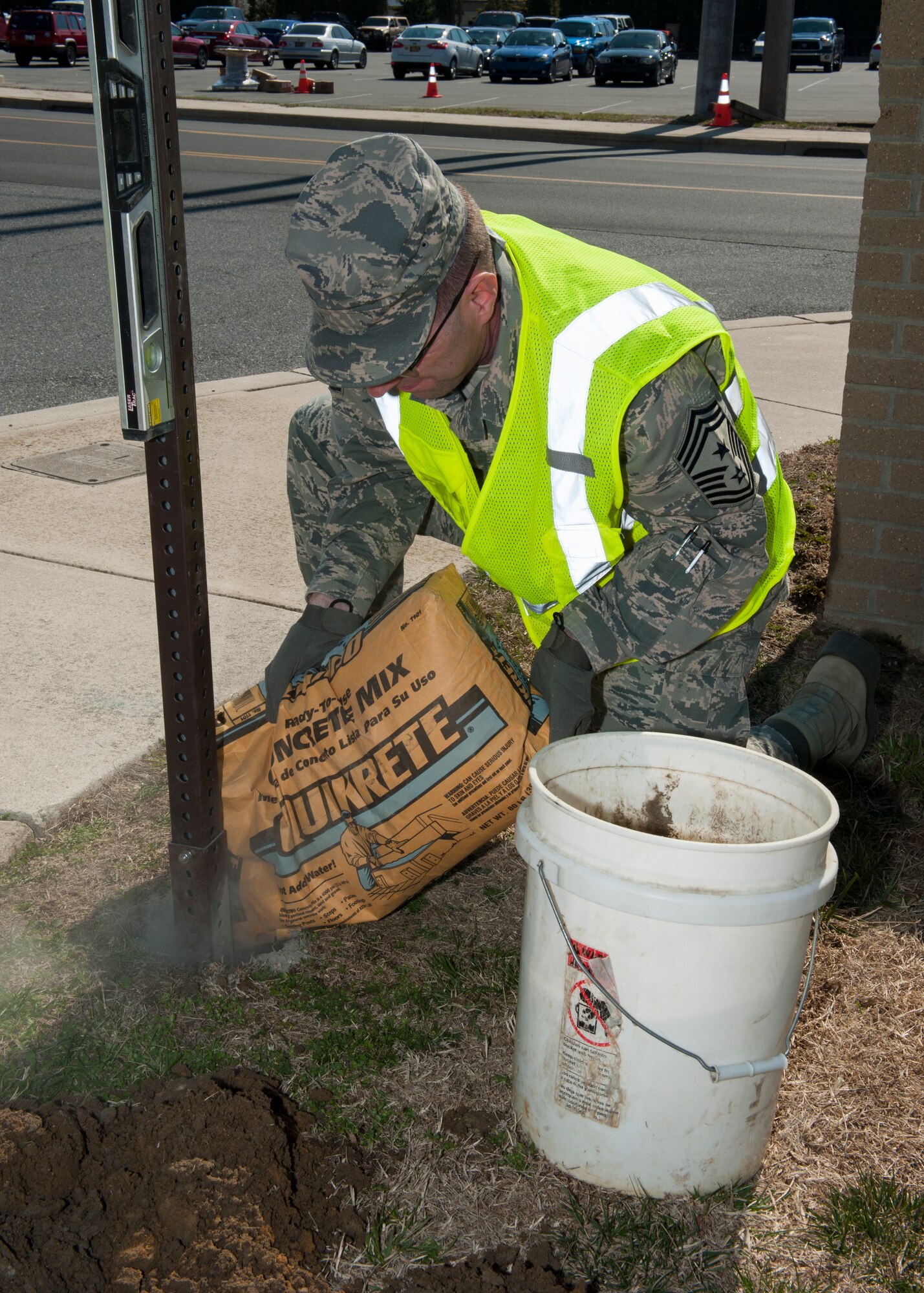 Chief Master Sgt. Stanley Cadell, 436th Airlift Wing command chief, pours a concrete mix into a hole to support a new stop sign April 1, 2015, at Dover Air Force Base, Del. The Commander to Work allows Col. Michael Grismer, 436th AW commander, and Cadell to spend time working with Airmen. (U.S. Air Force photo/Airman 1st Class Zachary Cacicia)