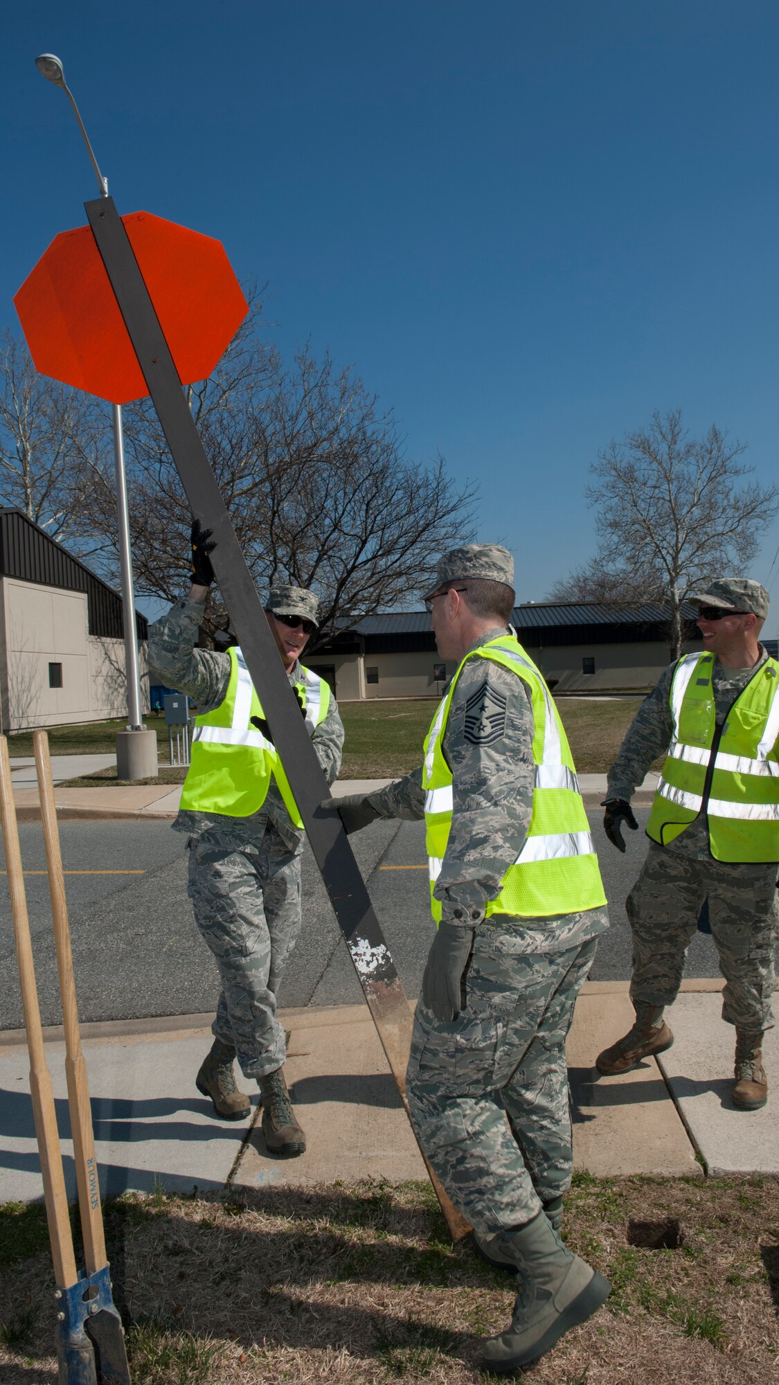 Col. Michael Grismer, 436th Airlift Wing commander, left, and Chief Master Sgt. Stanley Cadell, 436th AW command chief, center, remove an old stop sign April 1, 2015, at Dover Air Force Base, Del. Grismer and Cadell helped replace two old stop signs with newer “break-away” stop signs to meet Air Force safety standards. (U.S. Air Force photo/Airman 1st Class Zachary Cacicia)