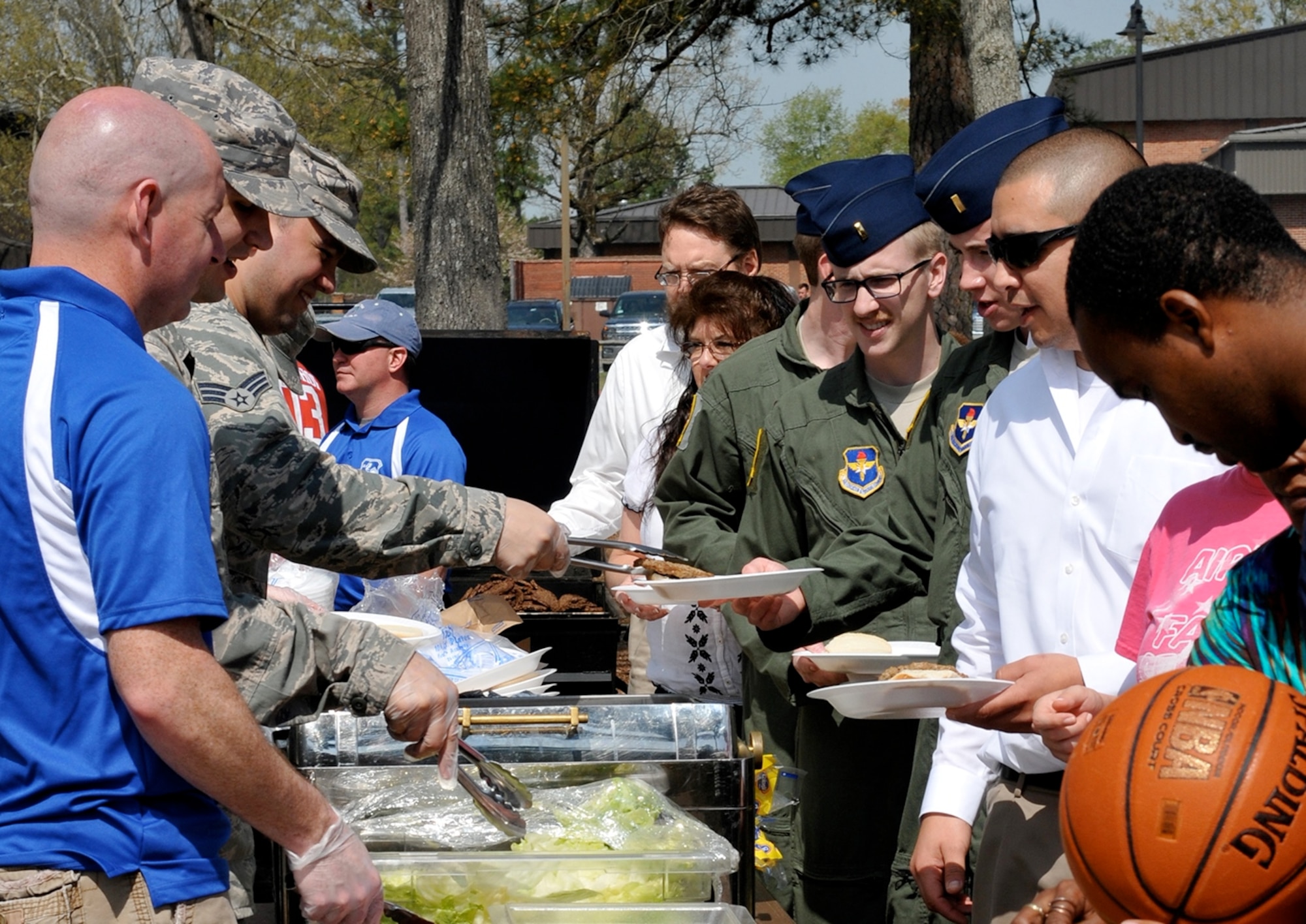 Team BLAZE members line up for free hamburgers during the Columbus Air Force Base post-Unit Effectiveness Inspection burger burn April 1 at Freedom Park on Columbus Air Force Base, Mississippi. Members also got a chance to participate in a variety of sport activities such as 3-on-3 basketball, 1-pitch softball, sand volleyball and free golf. (U.S. Air Force photo/Elizabeth Owens)