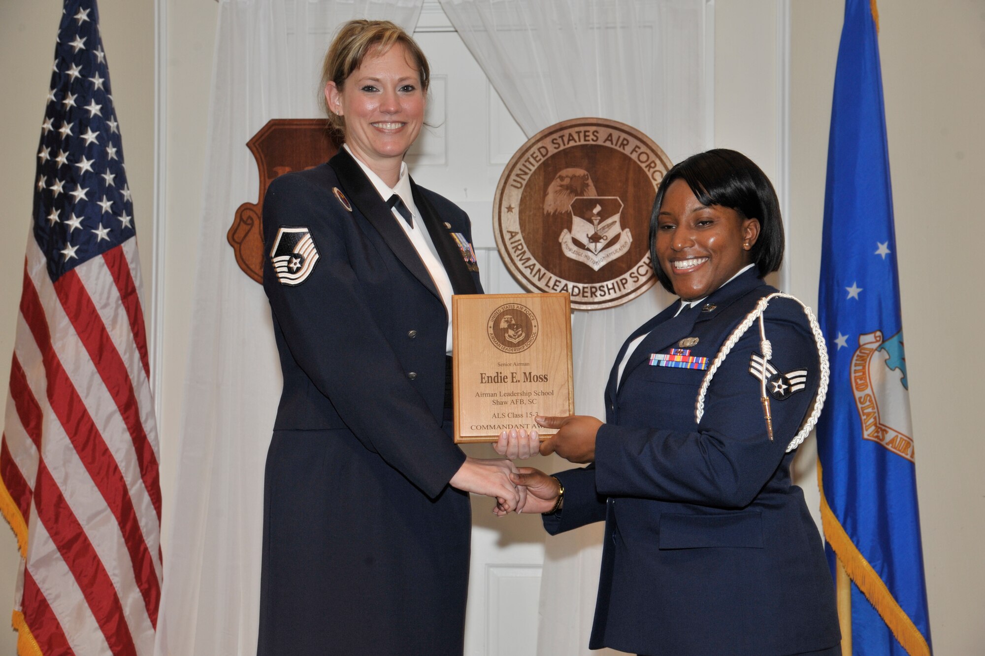 U.S. Air Force Senior Airman Endie Moss, 20th Security Forces Squadron, receives the Senior Master Sgt. David B. Reid Airman Leadership School commandant award from Master Sgt. Lindsey Wolf, 20th Force Support Squadron ALS commandant, during the ALS Class 15-3 graduation at Shaw Air Force Base, S.C., April 2, 2015. The Commandant’s award is given to the student who most exemplifies professional military qualities as chosen by their peers, the primary instructors, and the ALS commandant. (U.S. Air Force photo by Senior Airman Jonathan Bass/Released)