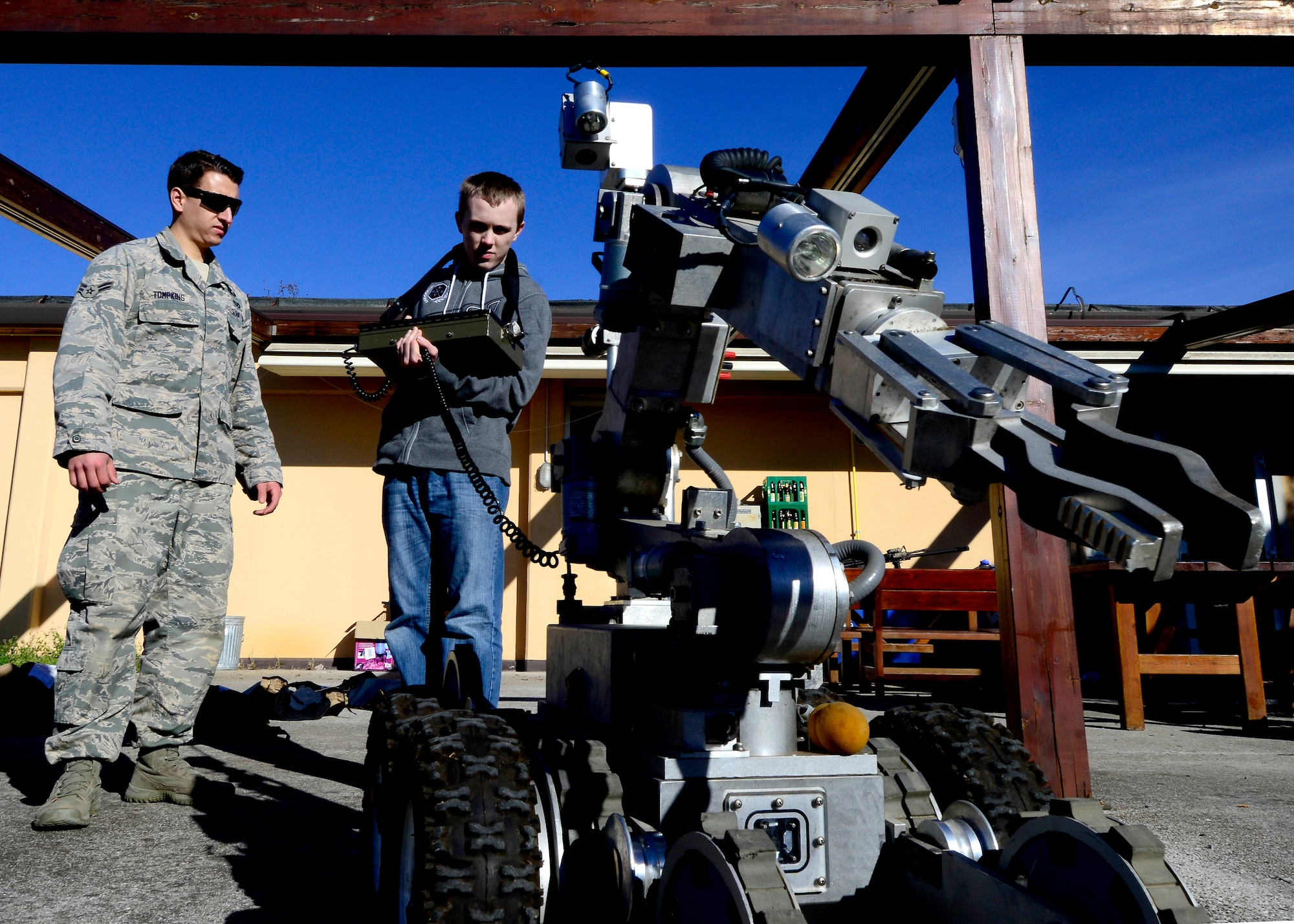 (From left) U.S. Force Airman 1st Class Taylor Tomkins, 31st Civil Engineer Squadron explosive ordnance apprentice, watches Jaiden Raymond, Aviano student, operate an F6A robot, April 2, 2015, at Aviano Air Base, Italy. During his visit to the 31 CES EOD flight, Raymond was given the opportunity to operate equipment used by EOD Airmen. (U.S. Air Force photo by Senior Airman Areca T. Wilson/Released)