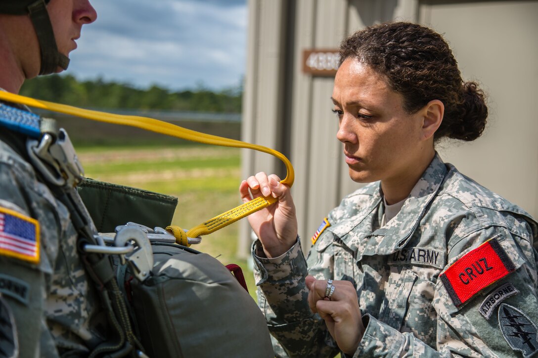 Army 1st Sgt. Sandrea Cruz, right, conducts a jumpmaster personnel inspection on a soldier, preparing him for a static-line parachute jump from an aircraft. Cruz leads more than 150 soldiers as the first sergeant for the 7th Special Forces Group’s (Airborne) Sustainment and Distribution Company. U.S. Army photo by Staff Sgt. Bryan Henson