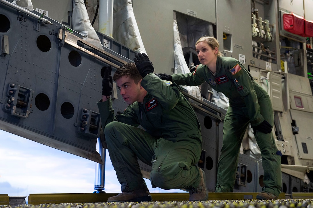 Air Force Airman 1st Class Nicholas Hendrickson, left, and Air Force Staff Sgt. Alyse M. Denittis guide a Tunner 60K aircraft cargo loader during Rapid Raptor training at the Joint Mobility Center on Joint Base Elmendorf-Richardson, Alaska, March 26, 2015. Hendrickson and Denittis are assigned to the 517th Airlift Squadron.