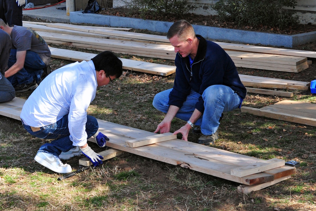 Col. Ken “Wolf” Ekman, 8th Fighter Wing commander, and 8th FW Airmen build part of the retaining wall for “Wolf Pack Garden” in front of the Sonlight Inn, March 14, 2015, at Kunsan Air Base, Republic of Korea. The garden is part of a community initiative to promote healthy living for Wolf Pack Airmen. (U.S. Air Force photo by Capt. Reba Good/Released)
