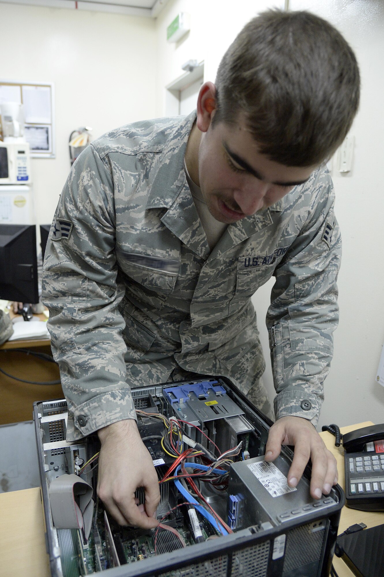 Senior Airman Blair, client service technician, repairs a computer at an undisclosed location in Southwest Asia April 3, 2015. During thier rotation CST Airmen have worked approximately 2,200 tickets are are cuttently assisting up to 150 customers a day with new account requests in addition to handling computer and telephone issues. Blair is deployed from Mountain Home Air Force Base, Idaho. (U.S. Air Force photo/Tech. Sgt. Marie Brown/RELEASED)