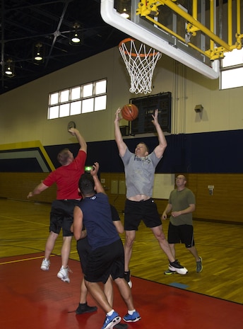 Service members with Headquarters and Headquarters Squadron jump to catch the rebound during H&HS’ basketball tournament inside the IronWorks Gym, April 3, 2015. H&HS organized the tournament to boost unit cohesion and morale through physical activity. A total of 15 teams of approximately 7 members participated.