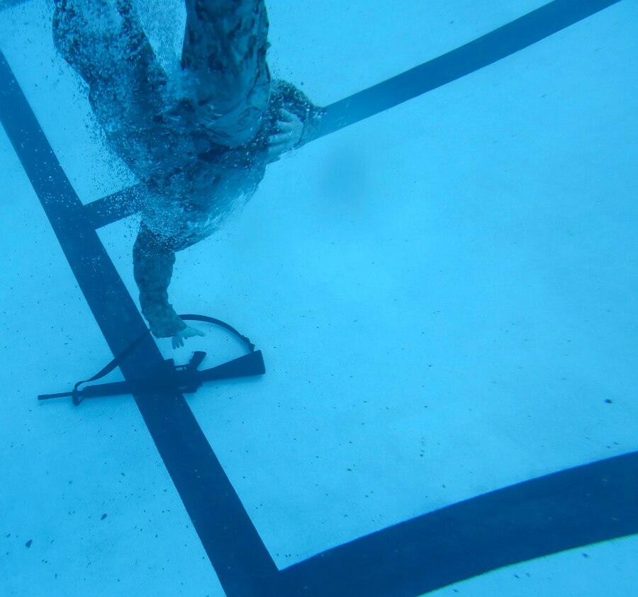 A U.S. Marine with the 26th Marine Expeditionary Unit recovers a rifle and helmet after conducting a deep water gear shed during a swim qualification course at the Area 5 pool aboard Marine Corps Base Camp Lejeune, N.C., March 17, 2015. The deep water gear shed tests Marines abilities to remove protective posture equipment while submerged in water. (U.S. Marine Corps photo by Cpl. Joshua W. Brown/Released)