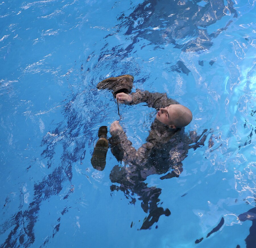 Cpl. Taylor K. Eversole, a U.S. Marine with the 26th Marine Expeditionary Unit, ties his boots together before inflating his pants during a swim qualification course at the Area 5 pool aboard Marine Corps Base Camp Lejeune, N.C., March 17, 2015. Marines must tread water for 10 minutes during the qualification to demonstrate they can properly use their uniform as a flotation device for survival in water. (U.S. Marine Corps photo by Cpl. Joshua W. Brown/Released)