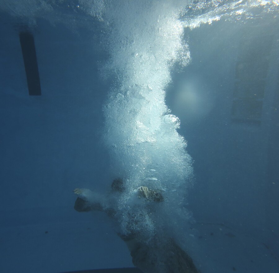 A U.S. Marine with the 26th Marine Expeditionary Unit dives under water and performs a self-rescue drill during a swim qualification course at the Area 5 pool aboard Marine Corps Base Camp Lejeune, N.C., March 17, 2015. To pass the course, Marines must demonstrate they can perform a self-rescue which simulates an emergency evacuation from a ship. (U.S. Marine Corps photo by Pfc. Dalton Precht/Released)