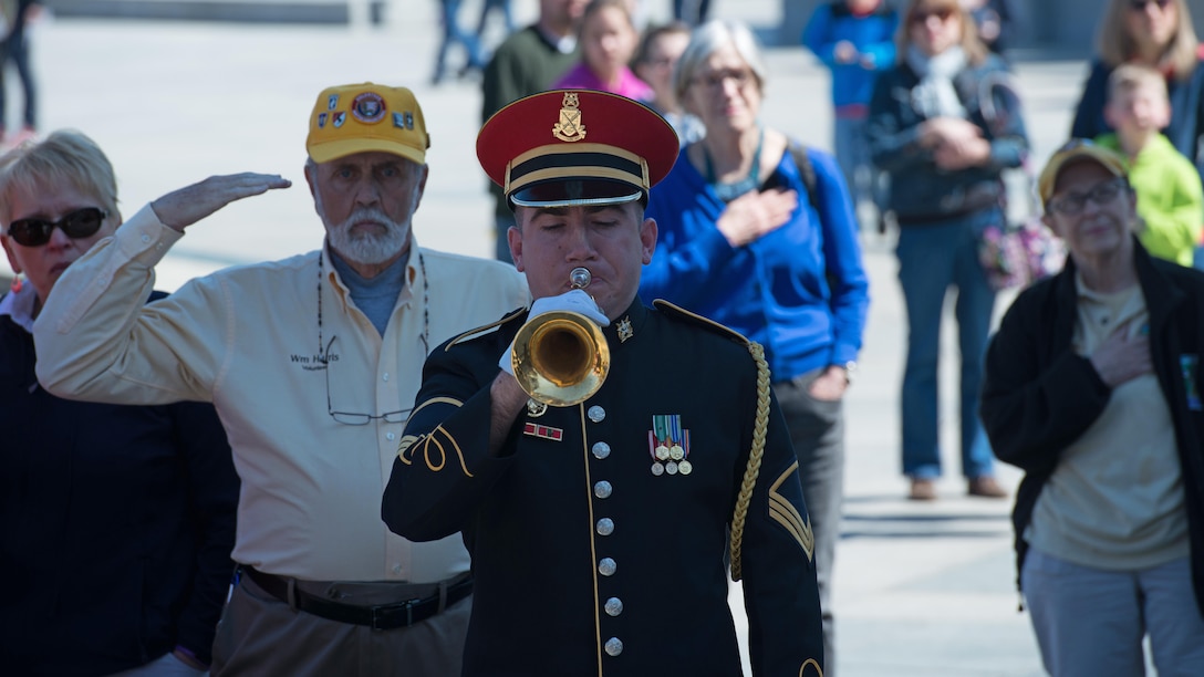 Staff Sgt. Kevin Gebo, a U.S. Army Band Pershing’s Own bugler, plays Taps for the veterans and the crowd, who gathered during a wreath laying ceremony in honor of the veterans of the Battle of Okinawa  at the World War II Memorial in Washington April 1, 2015. On April 1, 1945, allied forces invaded the island of Okinawa. The battle lasted 82 days amassing high totals of allied, Japanese and civilian casualties.