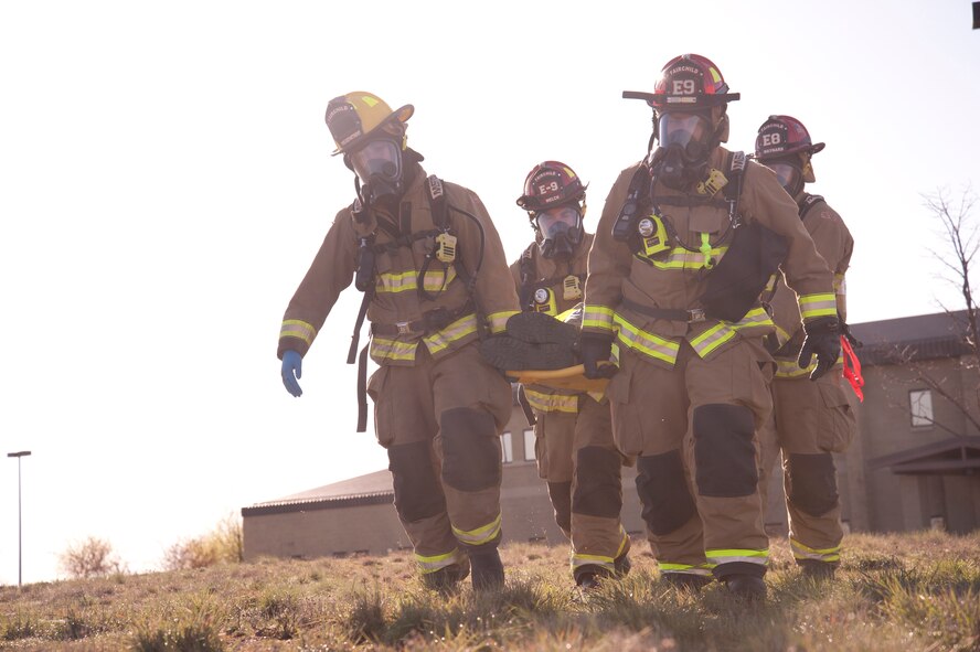 Firefighters from the 92nd Civil Engineer Squadron carry a victim on a stretcher during a emergency management exercise March 30, 2015, at Fairchild Air Force Base, Wash. The firefighters transported the victim away from a simulated demolition site during the exercise. (U.S. Air Force photo/Airman 1st Class Nicolo J. Daniello)
