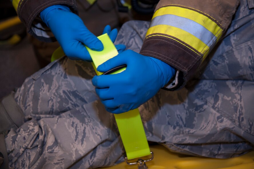 A firefighter from the 92nd Civil Engineer Squadron straps a victim’s legs to a stretcher during an emergency management exercise March 30, 2015, at Fairchild Air Force Base, Wash. Emergency responders participated in scenarios that tested their response time and proficiency for real world response events. (U.S. Air Force photo/Airman 1st Class Nicolo J. Daniello)