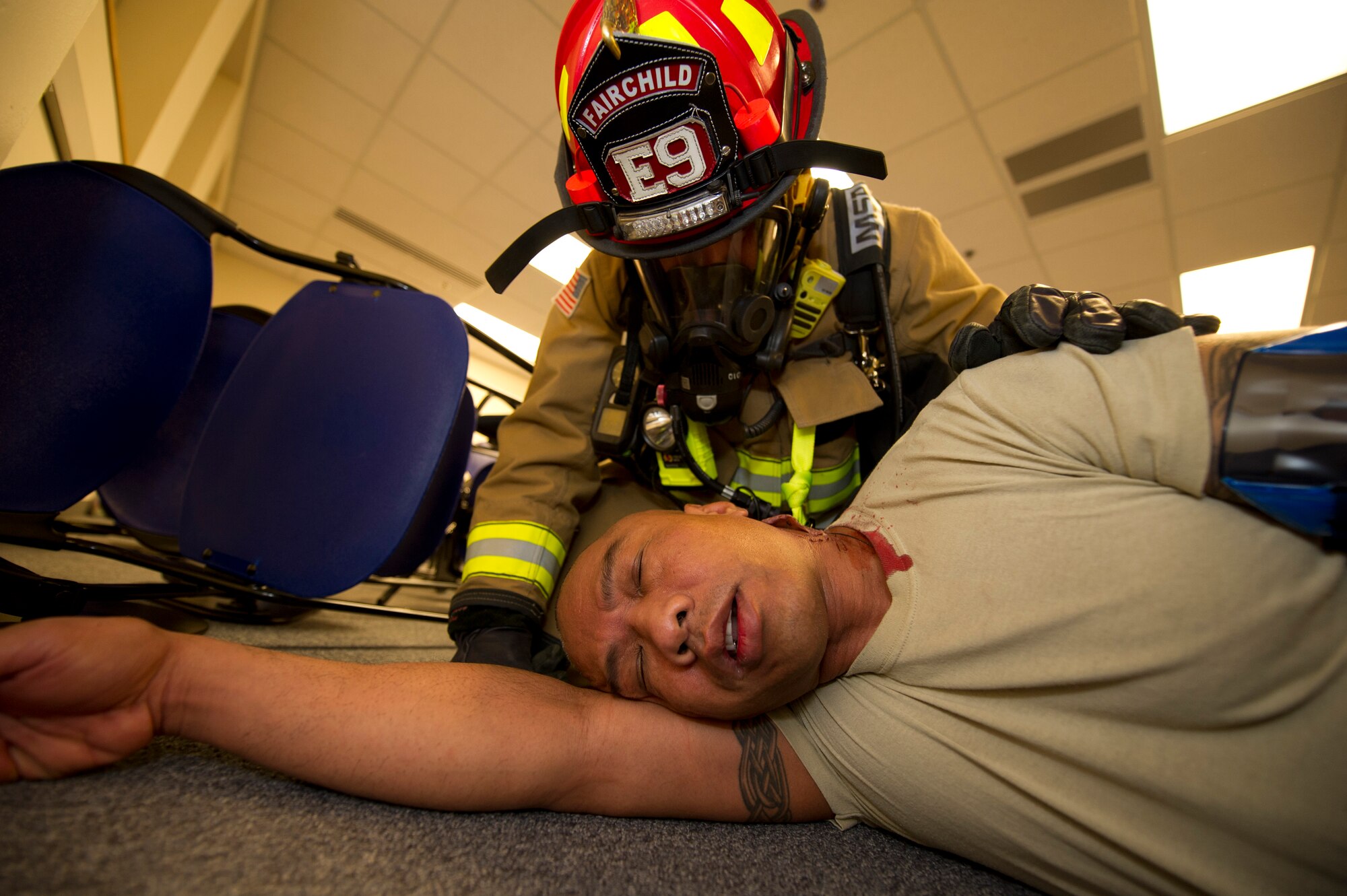 A firefighter from the 92nd Civil Engineer Squadron assists Master Sgt. Ray Ordonio, 92nd Maintenance Squadron accessory flight assistant flight chief, during the emergency management exercise March 30, 2015, at Fairchild Air Force Base, Wash. Firefighters, along with other members of Team Fairchild, responded to a simulated explosion, active shooter and hostage situation. (U.S. Air Force photo/Airman 1st Class Nicolo J. Daniello)