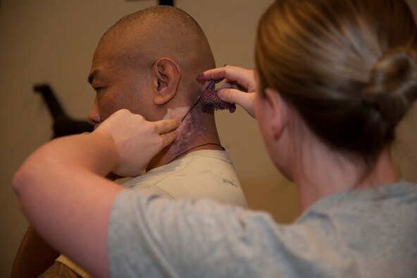 Staff Sgt. Amy Williams, 92nd Aerospace Medicine Squadron certified dental assistant, applies make-up to Master Sgt. Ray Ordonio, 92nd Maintenance Squadron accessory flight assistant flight chief, as part of a emergency management exercise March 30, 2015, at Fairchild Air Force Base, Wash. To make the exercise appear more realistic, make-up was applied to role players. (U.S. Air Force photo/Airman 1st Class Nicolo J. Daniello)
