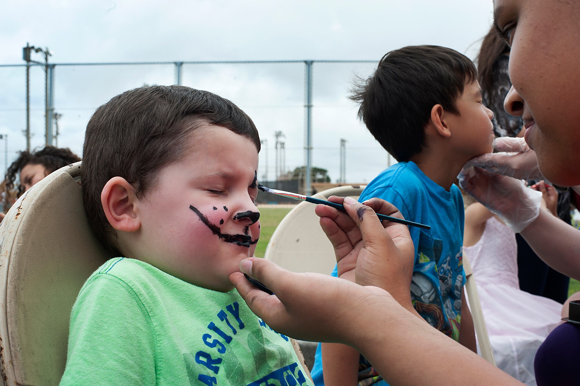 A volunteer paints Blake Daughtery's face during EGGsplosion, Kadena Air Base, Japan, April 4, 2015. EGGsplosion is an annual event and includes multiple Easter egg hunts, cultural demonstrations, food and prizes. (U.S. Air Force photo by Staff Sgt. Rachelle Coleman)