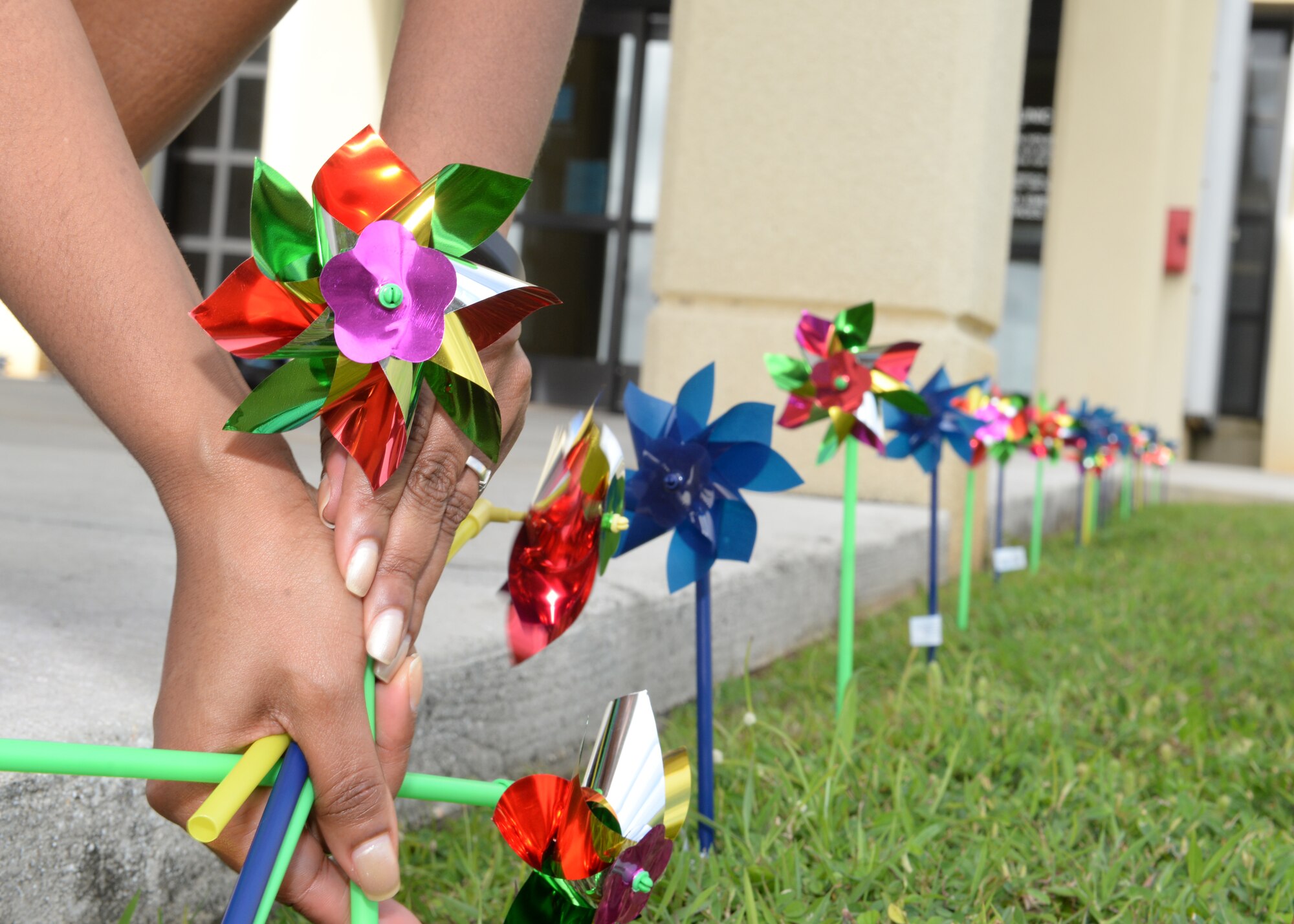 A member of Team Andersen places a pinwheel in the ground during a pinwheel planting event for Child Abuse Prevention Month April 3, 2015, at Andersen Air Force Base, Guam. This year’s theme, “Know the Difference-Discipline is Not Abuse,” emphasizes the U.S. Department of Health and Human Services effort to educate parents on disciplining children without being abusive. (U.S. Air Force photo by Senior Airman Amanda Morris/Released)