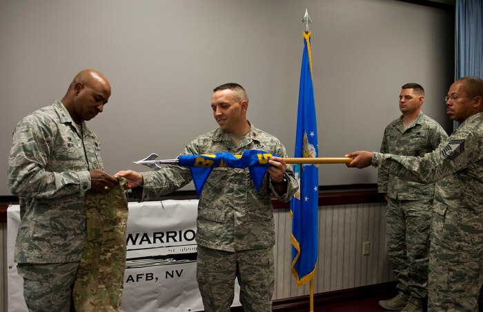 Col. Richard Neal, 799th Air Base Group commander, and Maj. Jesse Goens, 99th Ground Combat Training Squadron commander, prepare to place a cover over the 99th GCTS guidon, officially inactivating the 99th GCTS, at Nellis Air Force Base, Nev., April 1, 2015. Before inactivating, the 99th GCTS received the first Air Combat Command Security Forces Order of the Shield unit awar Feb. 6, 2015. The 99th GCTS was responsible for conducting training on Silver Flag Alpha, where Airmen taught and evaluated security forces members on air base defense skills. (U.S. Air Force photo by Airman 1st Class Jake Carter)