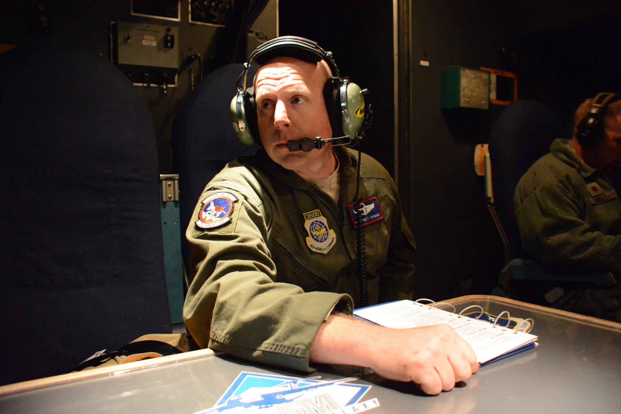Master Sgt. Matt Thomas, 22nd Airlift Squadron section chief of loadmaster standardization and evaluation, listens to his headsets and watches out the window during the preflight checklist aboard the record-setting C-5M Super Galaxy. (U.S. Air Force photo by Airman 1st Class Amber Carter) 