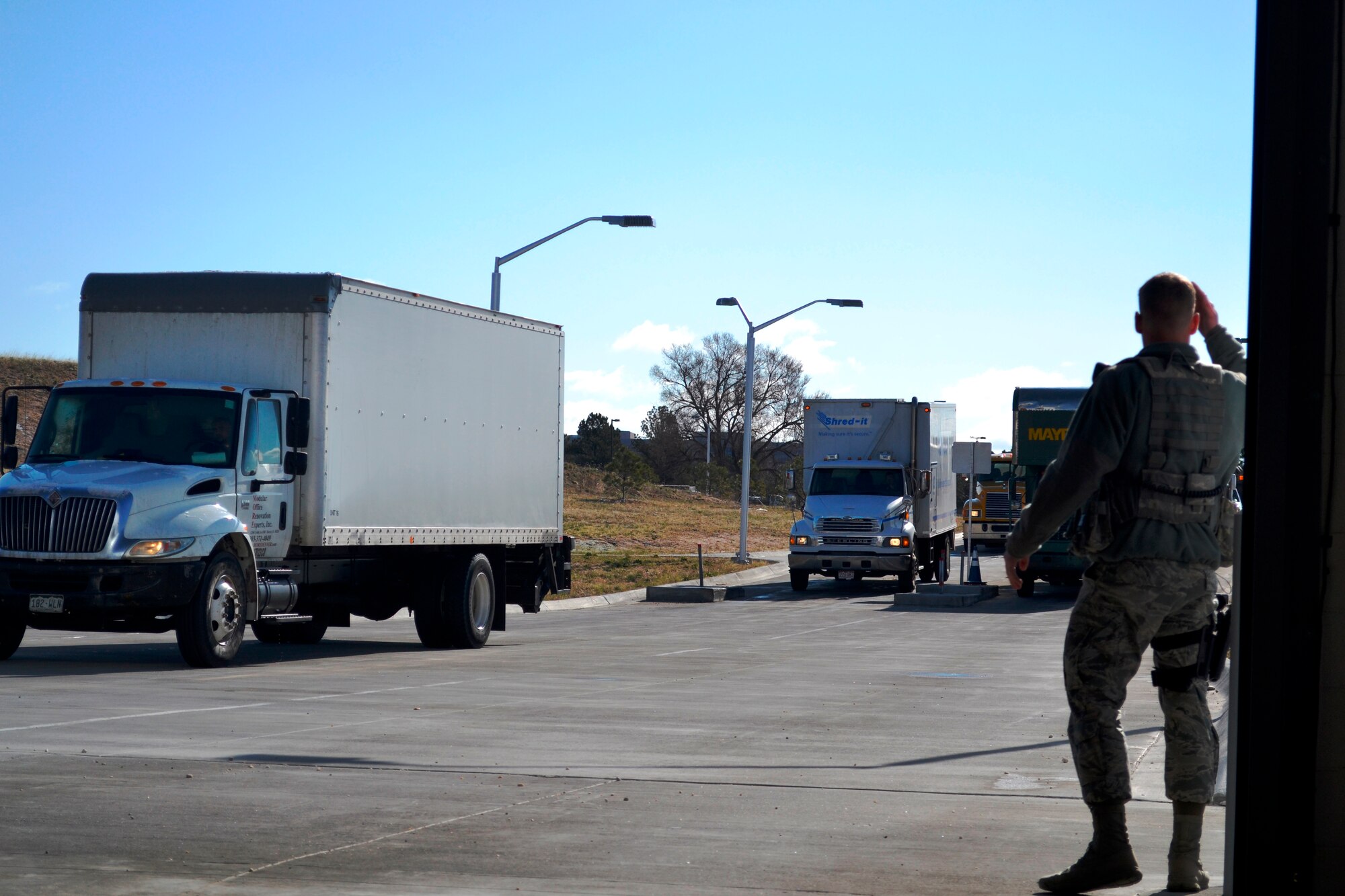 Airman 1st Class Blake Boren, 10th Security Forces Squadron, waves vehicles toward the Large Vehicle Inspection Station here April 3, 2015. The station, used to inspect contractor and commercial vehicles before they enter the installation, was recognized for its design excellence by the Air Force's 2014 Design Award Program. The station was also recognized by the U.S. Green Building Council for its environmental sustainability. (U.S. Air Force photo/Ray Bowden)