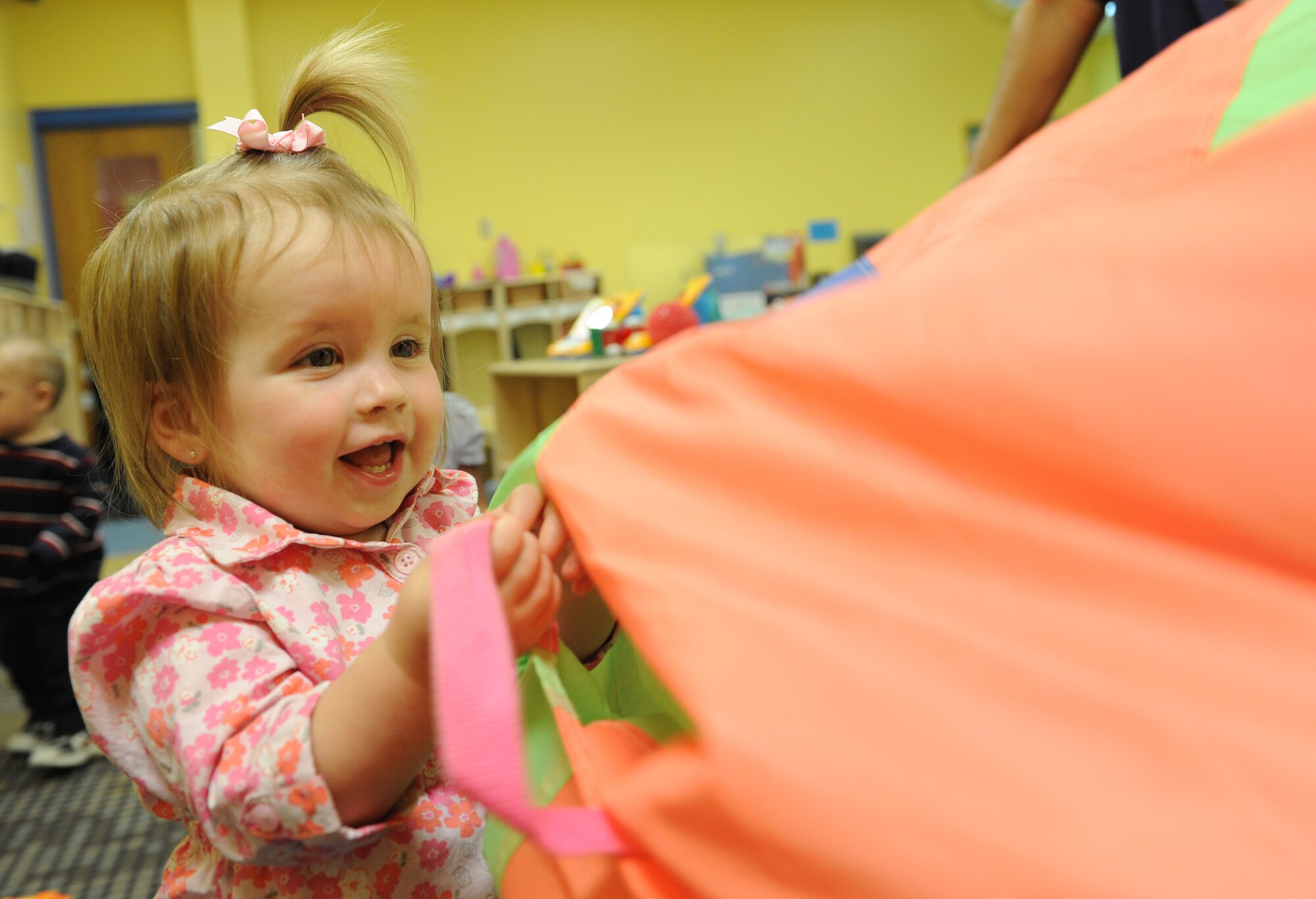 Abbey Mansfield, daughter of Senior Airman William Mansfield, 81st Logistics Readiness Squadron vehicle maintainer, plays with a parachute March 3, 2015, at the Keesler Child Development Center, Keesler Air Force Base, Miss. The CDC uses hands-on learning techniques to help children ranging from 6 weeks to 5 years old learn reading, speaking and comprehension skills. (U.S. Air Force photo by Senior Airman Holly Mansfield)