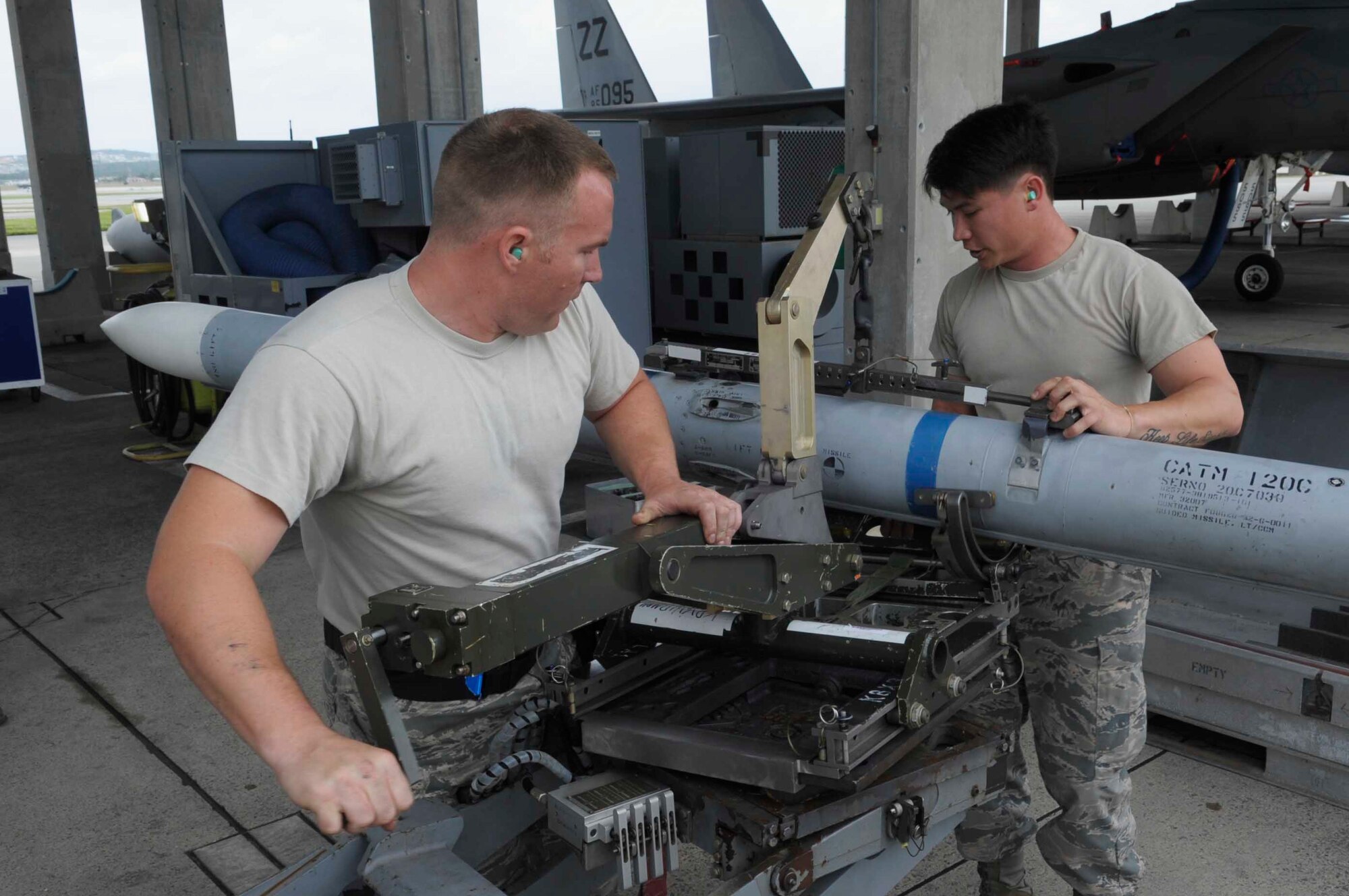U.S. Air Force Staff Sgt. Sean Lever, 44th Aircraft Maintenance Unit weapons load crew chief, secures a missile into place while Airman 1st Class Drew Kennett, 44th Aircraft Maintenance Unit weapons load crew member, lowers it into place at a weapons load competition at Kadena Air Base, Japan, April 6, 2015. The weapons load competition is a tradition held to raise morale, give Airmen motivation to outperform their peers and set a higher standard for crews to come. (U.S. Air Force photo by Airman 1st Class Zackary A. Henry/Released)