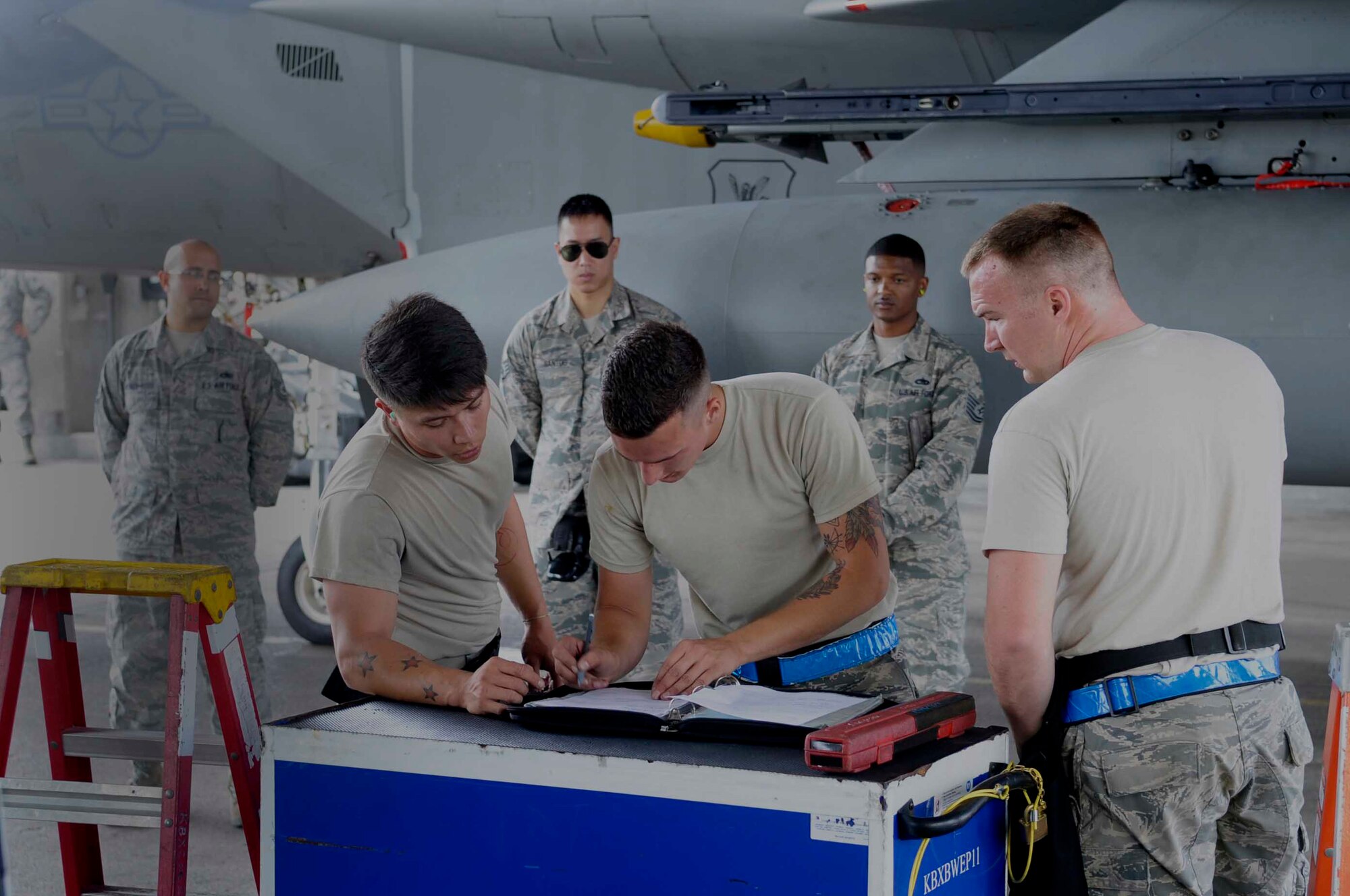 A group of Airmen from the 44th Aircraft Maintenance Unit with their supervision complete the final technical orders during a weapons load competition at Kadena Air Base, Japan, April 6, 2015. Competitions promote teamwork among weapons load crews and allow supervisors to evaluate their teams' strengths and weaknesses while under pressure. (U.S. Air Force photo by Airman 1st Class Zackary A. Henry/Released)