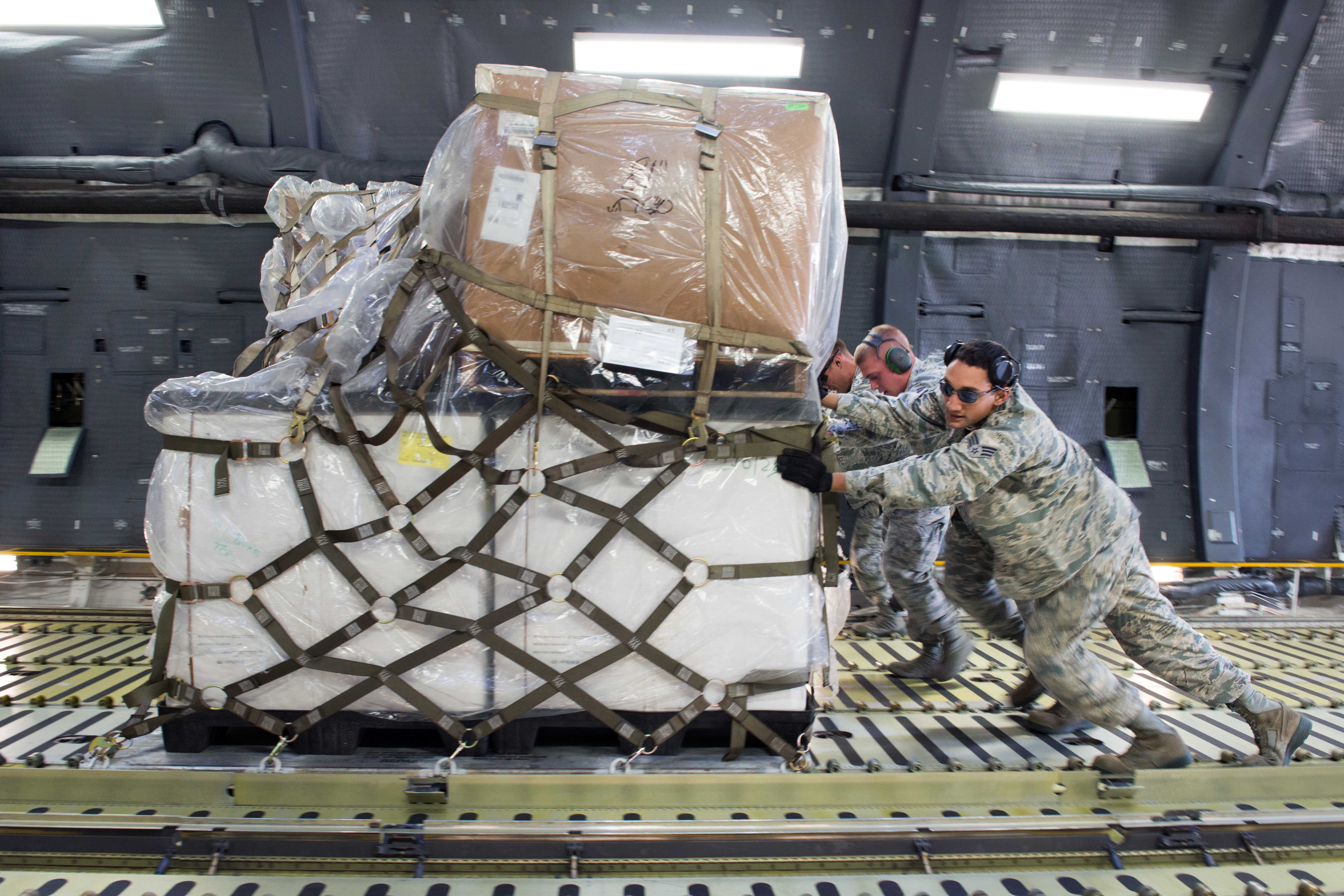 Airmen push a pallet full of ropes and chains onto a C-5M Super Galaxy ...