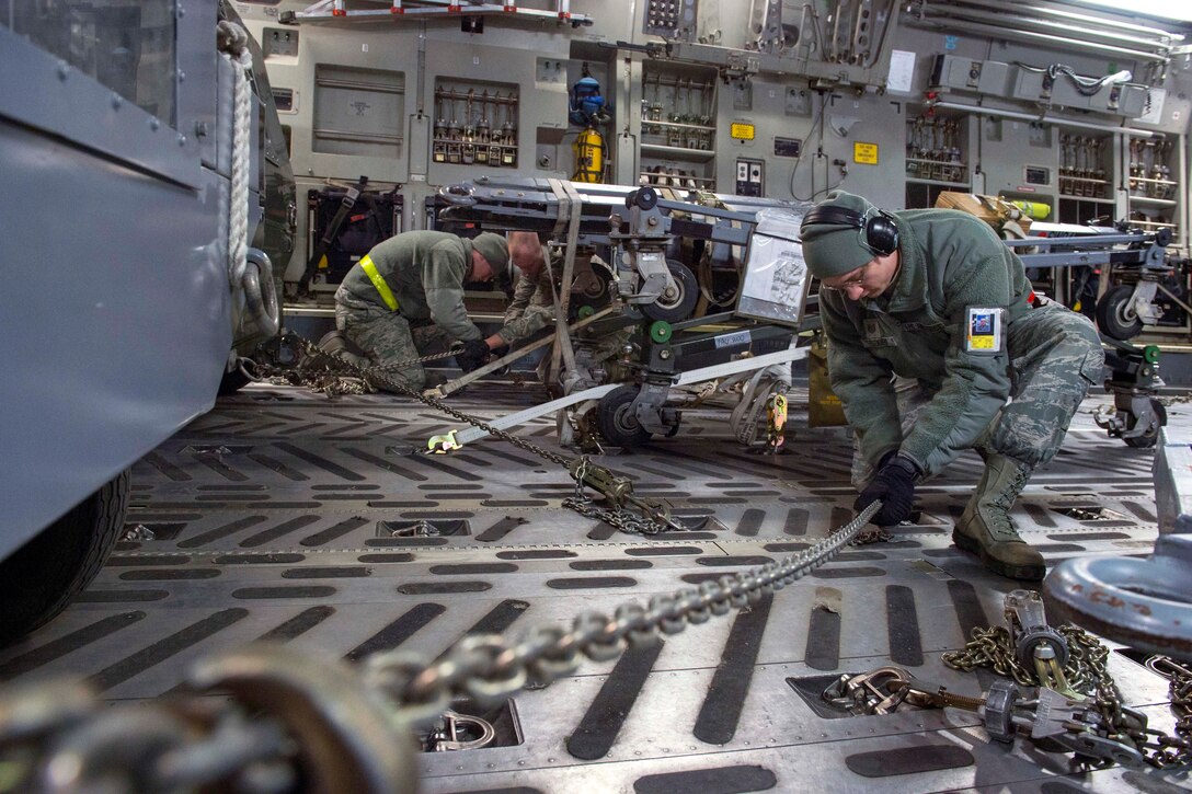 Airmen tighten chains to secure cargo on a C17 Globemaster III