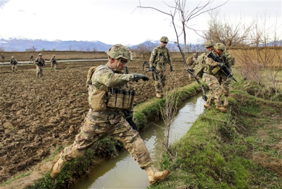 U.S. soldiers leap over a canal after patrolling through a field near Bagram Airfield, Afghanistan, March 24, 2015. The soldiers are assigned to the 101st Airborne Division's 3rd Battalion, 187th Infantry.