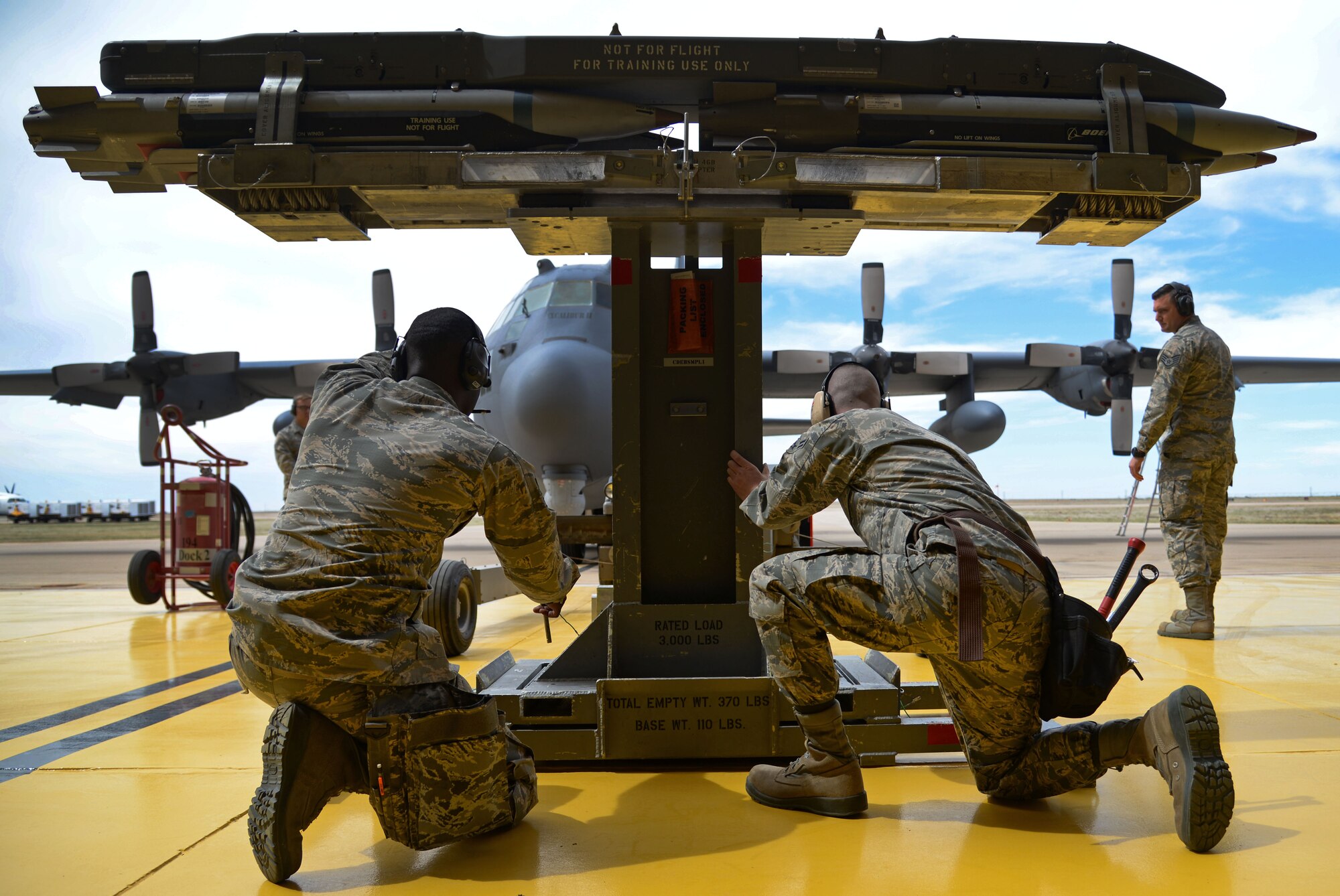 U.S. Air Force Staff Sgt. Olin Smith and Airman 1st Class Ryan Burtis, 27th Special Operations Maintenance Squadron AC-130 armament shop, transition a loading extension to transport and raise inert munitions during a load competition April 6, 2015 at Cannon Air Force Base, N.M. Crews worked diligently to showcase their skills to both Col. Ben Maitre, 27th Special Operations Wing commander, and Chief Master Sgt. Randy Scanlan, 27th SOW command chief, a prior weapons troop himself, who were among the distinguished spectators and evaluators present during the competition. (U.S. Air Force photo/Staff Sgt. Alex Mercer)